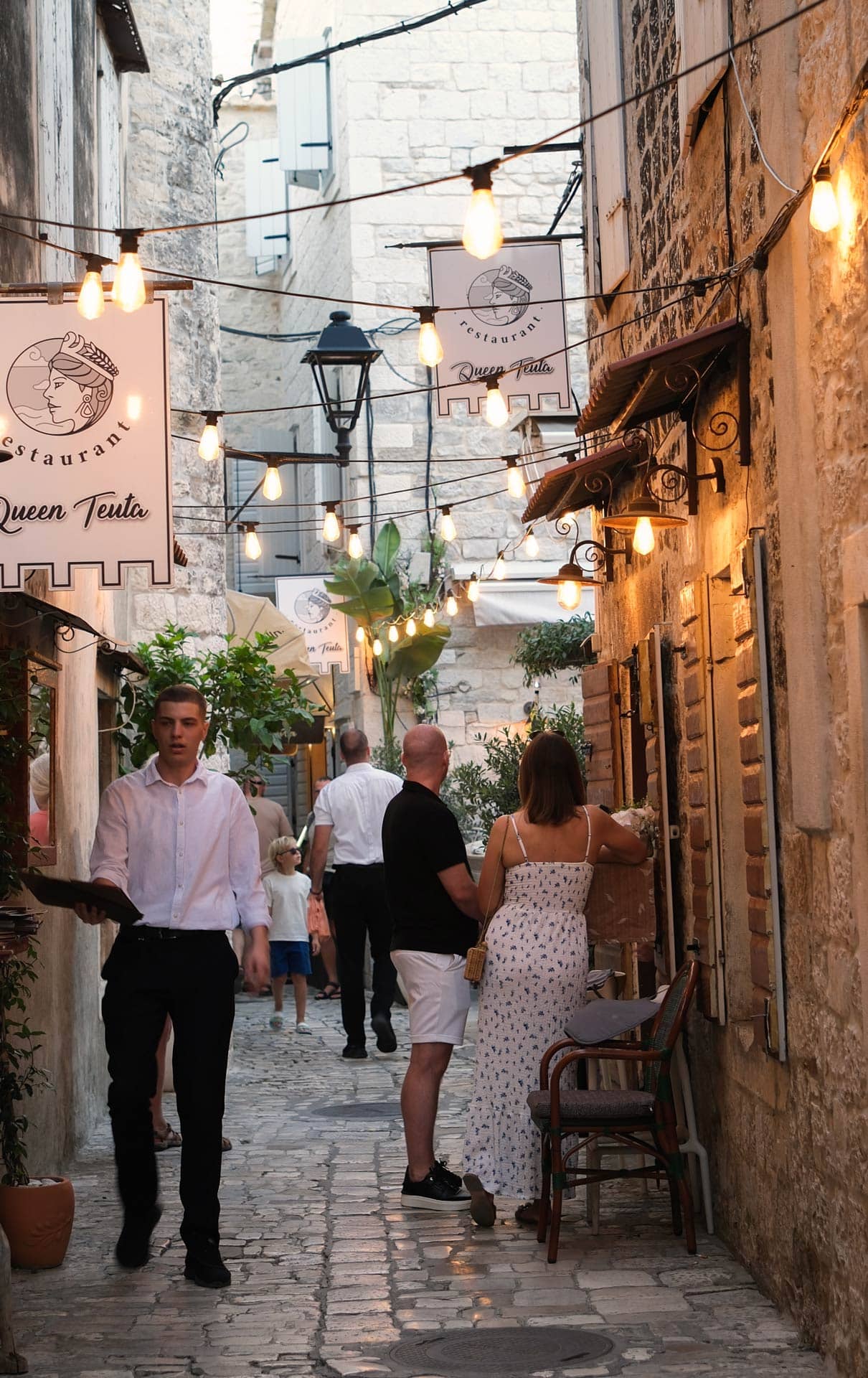 Gemütliche Gasse vor einem Restaurant in Kroatien mit Beleuchtung zwischen den Dächern