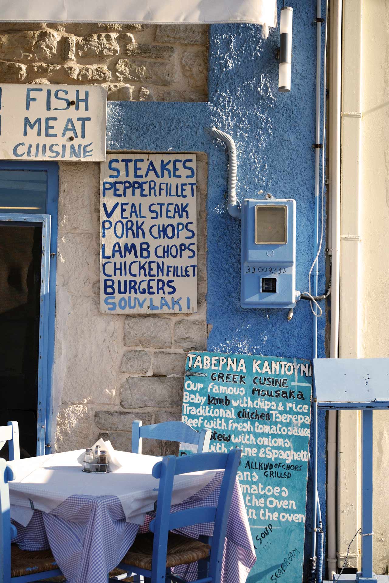 En restaurang i Megasini med blåa stolar och skyltar 