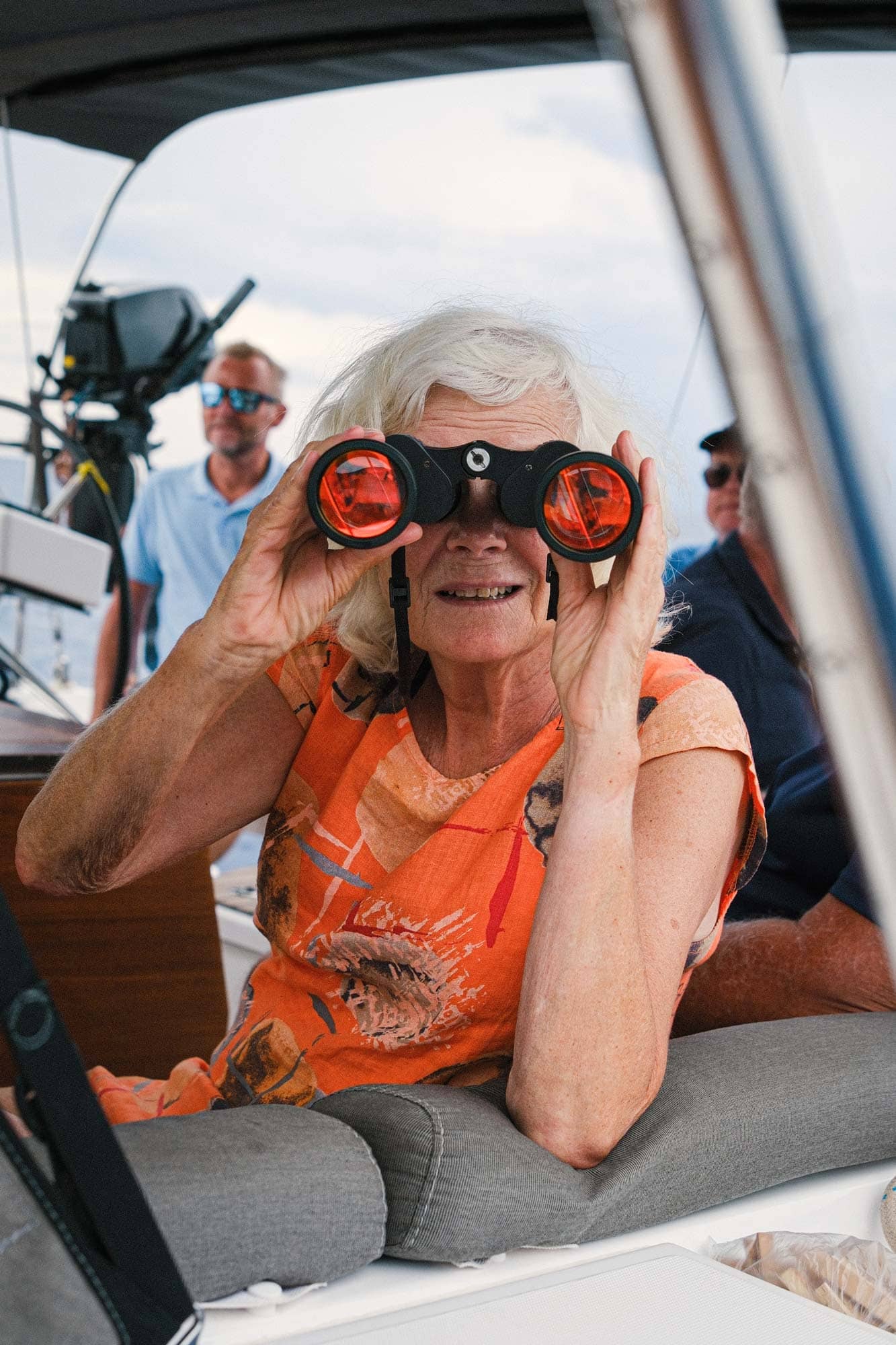 Ældre kvinde kigger ud mod havet i en kikkert.