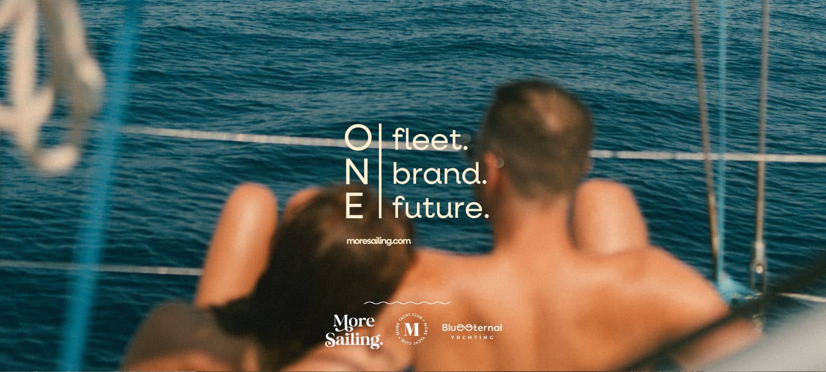 Zwei Personen sitzen auf einem Segelboot und blicken aufs Meer hinaus.