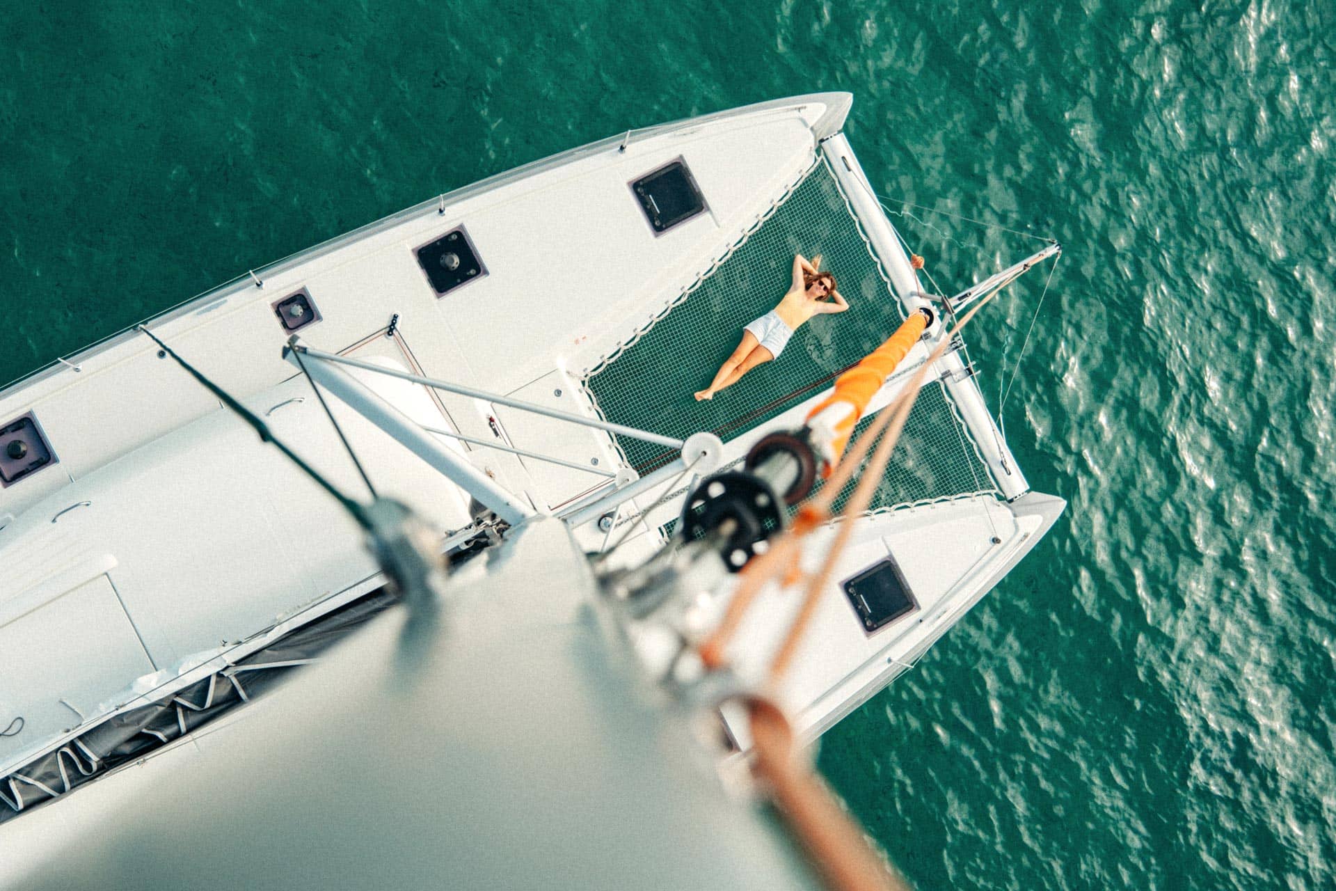 Woman sunbathing in the net of an Excess 11 catamaran