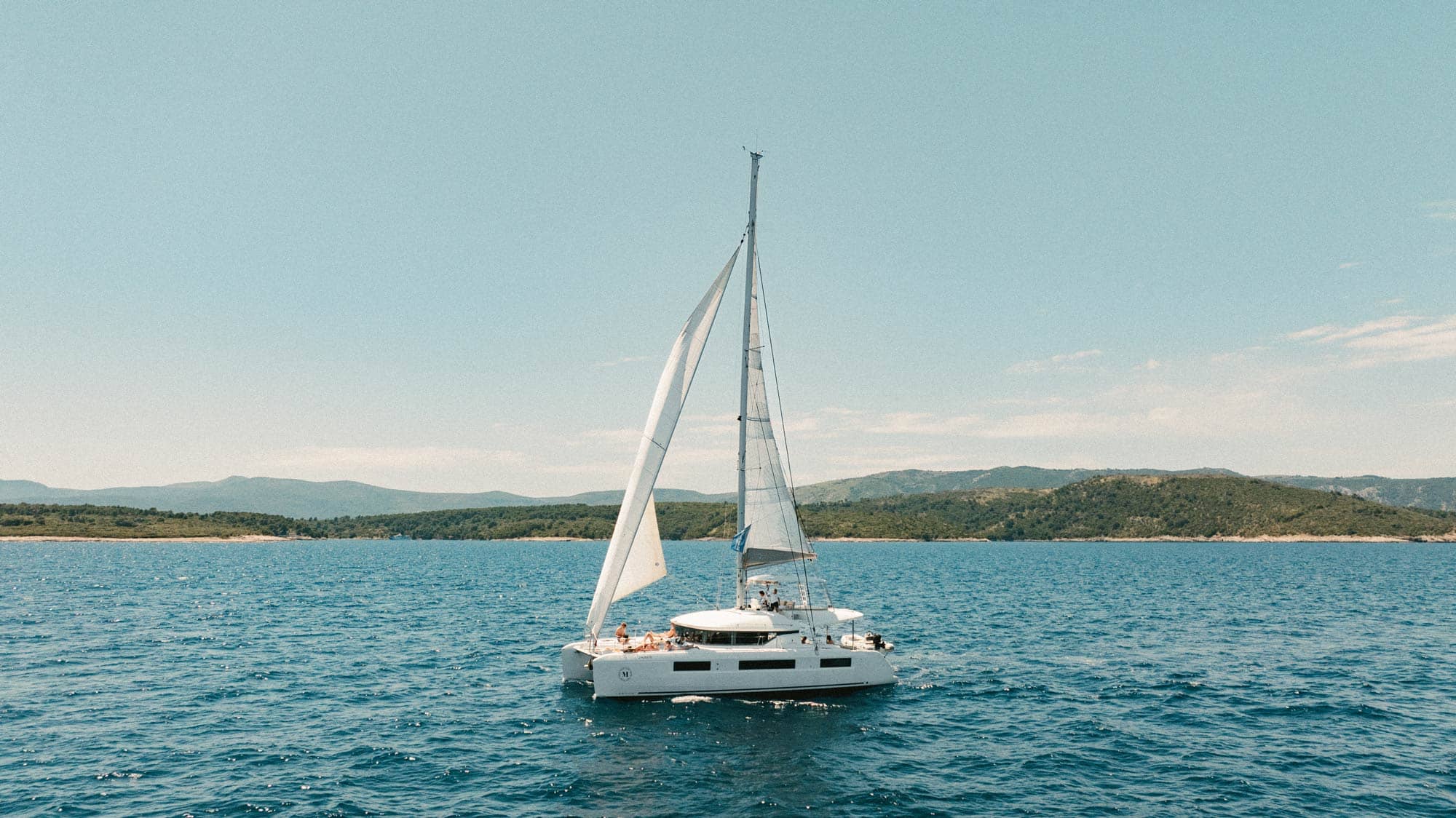Catamaran sailing with guests on board.