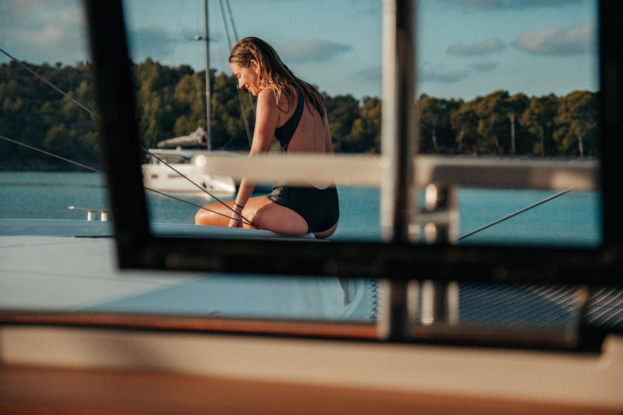 Frau sitzt im Badeanzug am Rand der Yacht