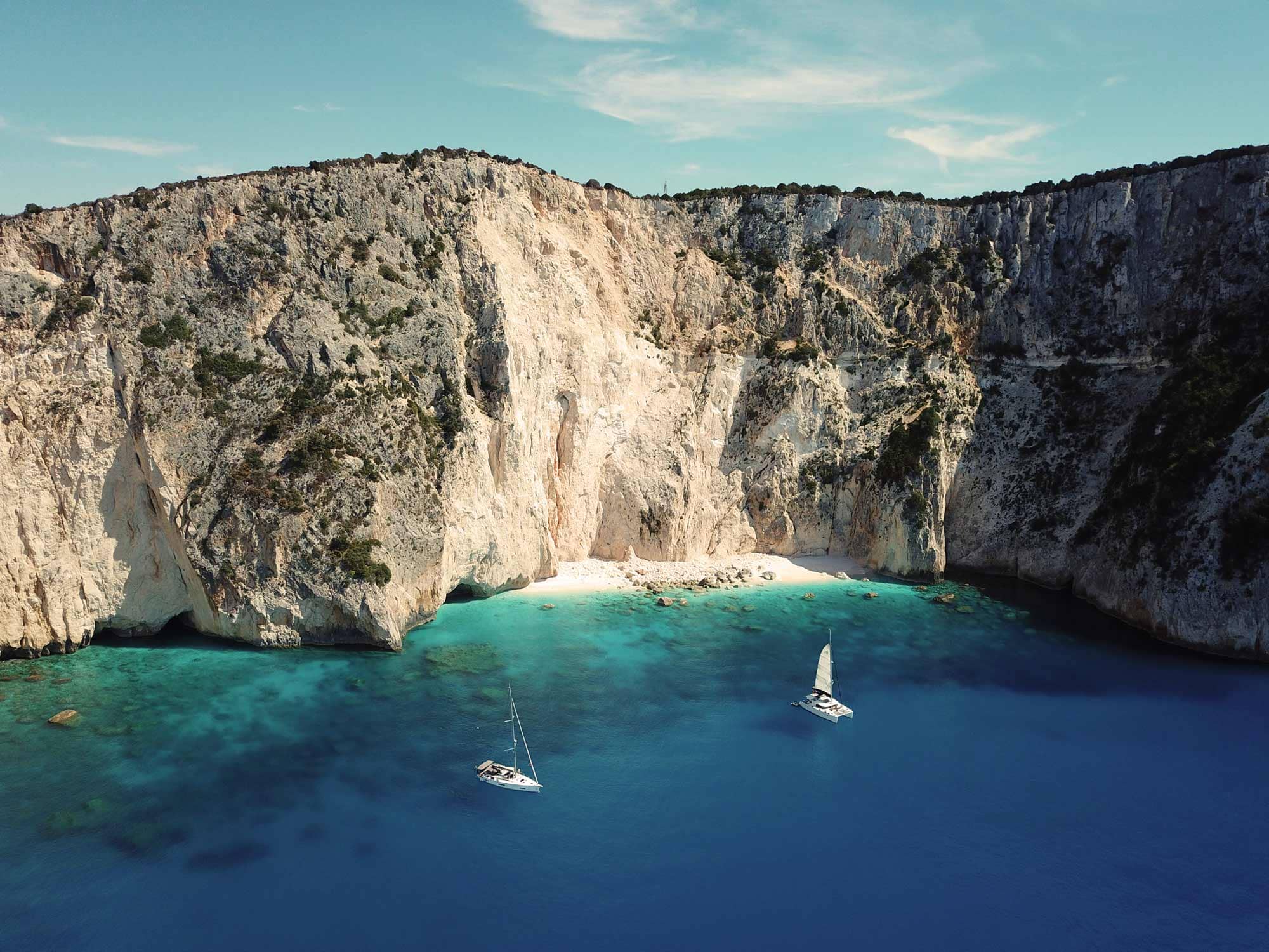 Im Mittelmeer vor einer hohen Klippe ankerndes Segelboot