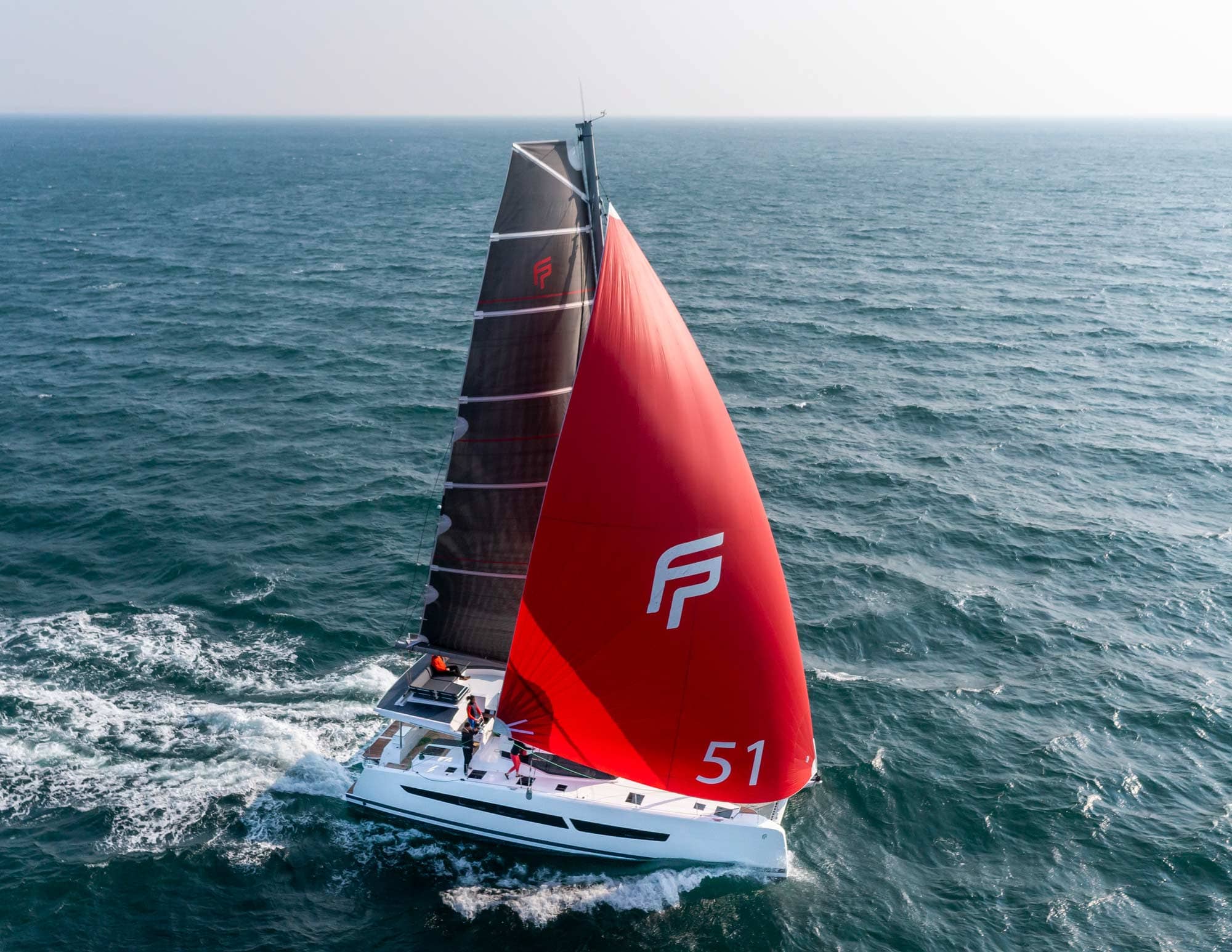 An Aura 51 model Fountaine Pajot catamaran. Sailing with a black and red sail 
