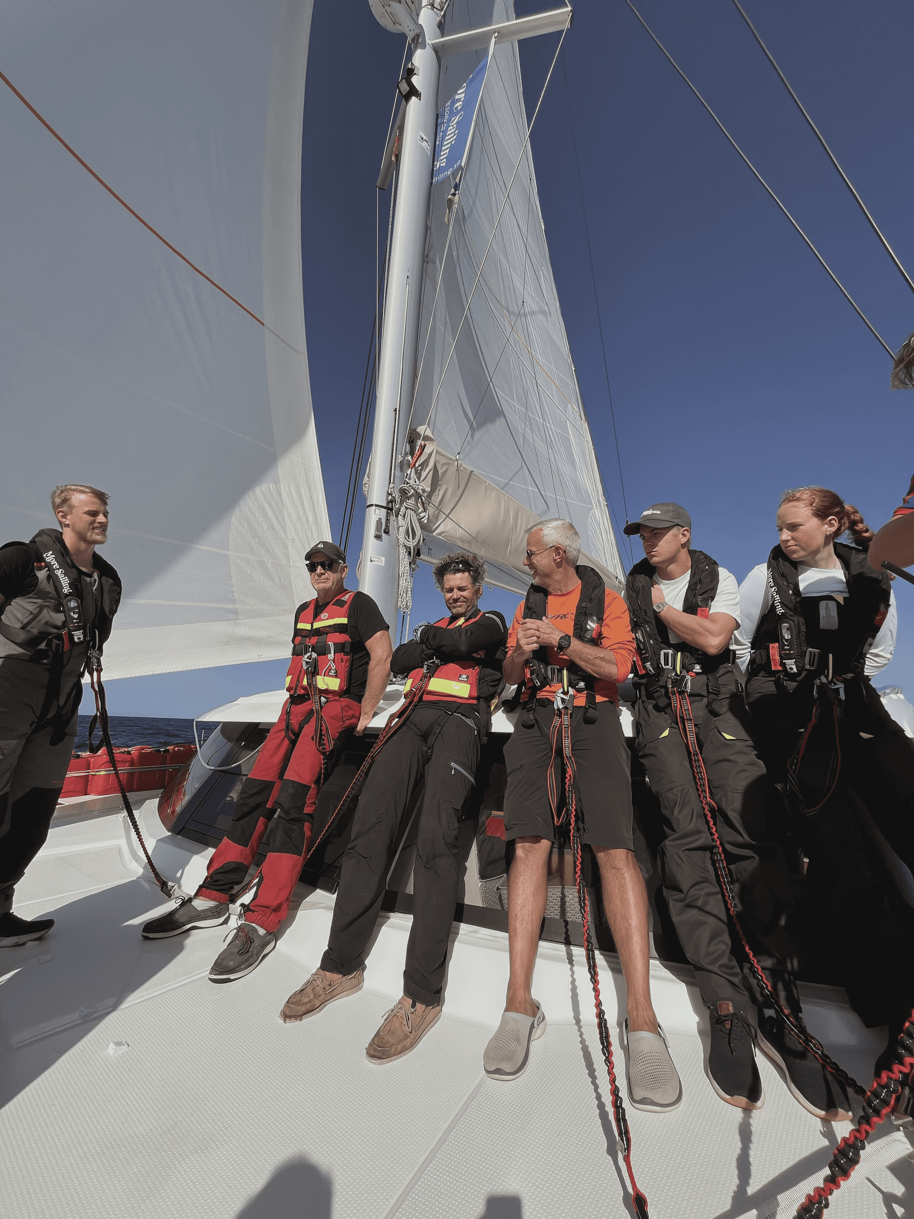 Kurseltagare står på däck i solen på en katamaran 