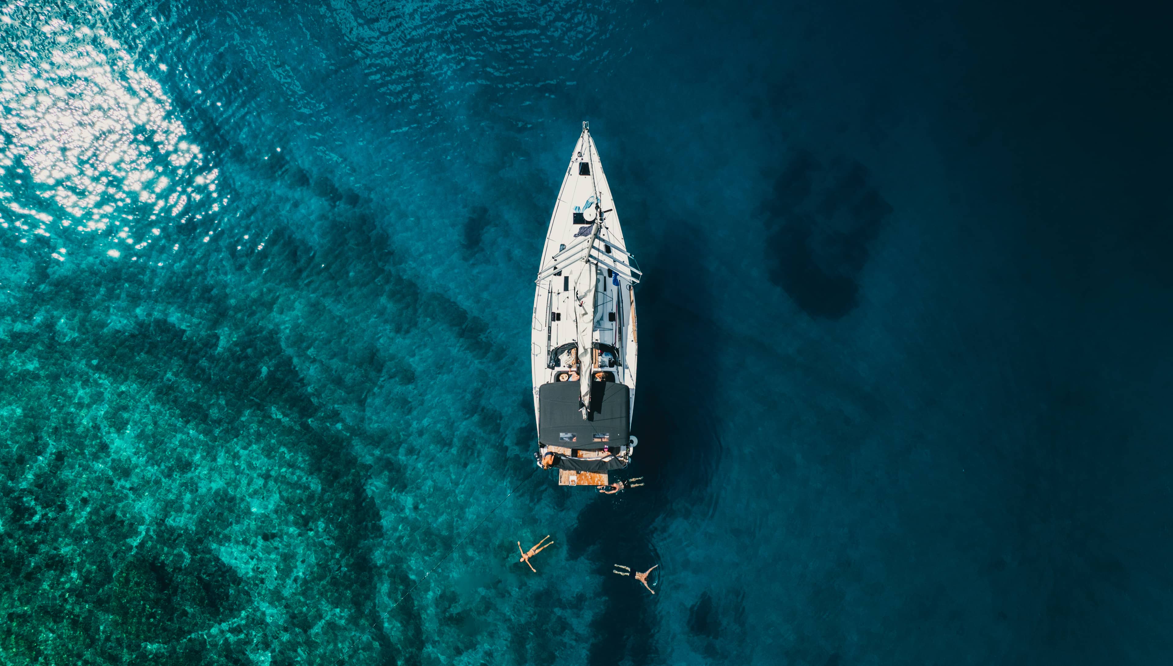 Ein Einrumpfboot liegt in türkisfarbenem Wasser vor Anker.