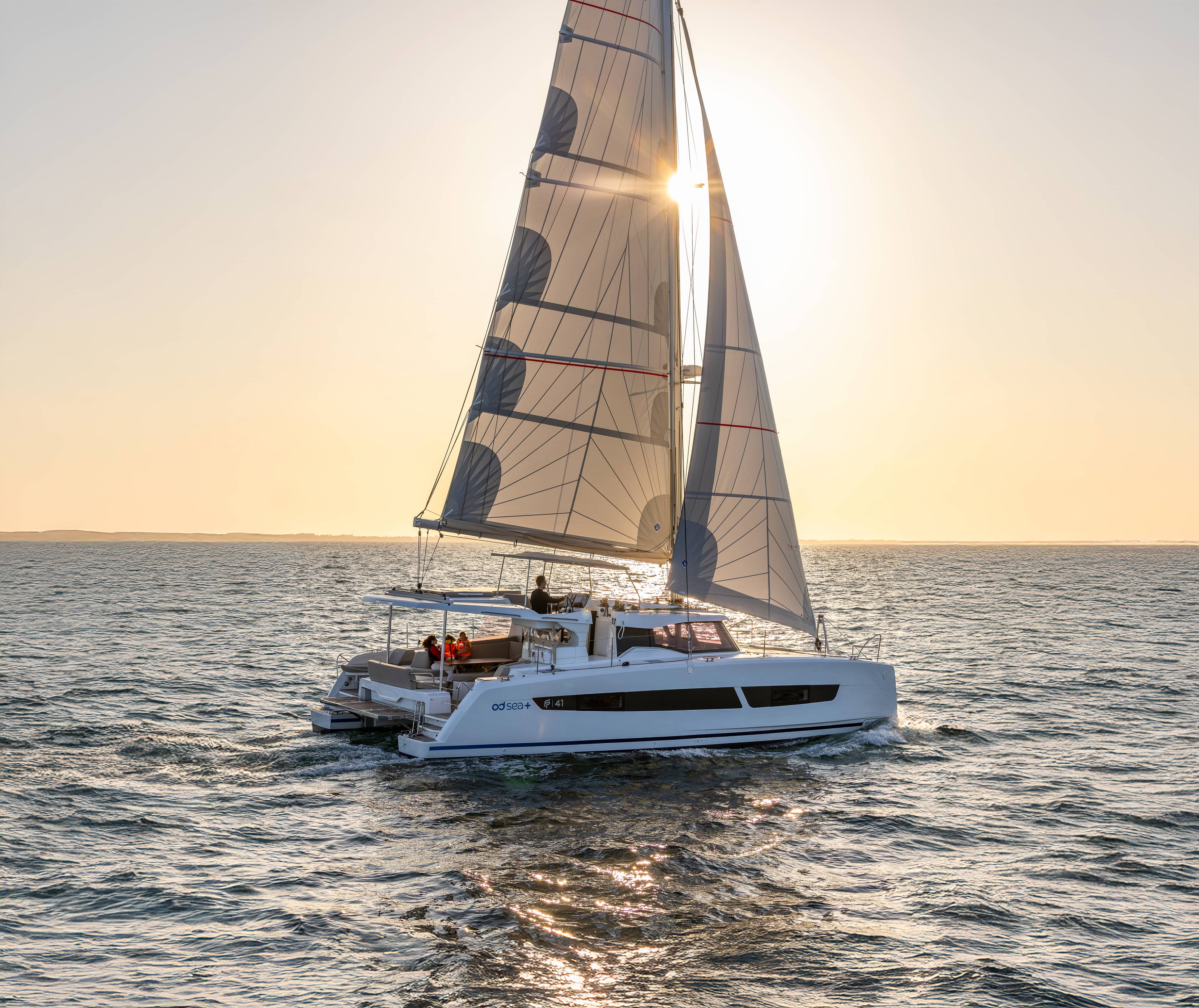 Katamaran seglar i solnedgången