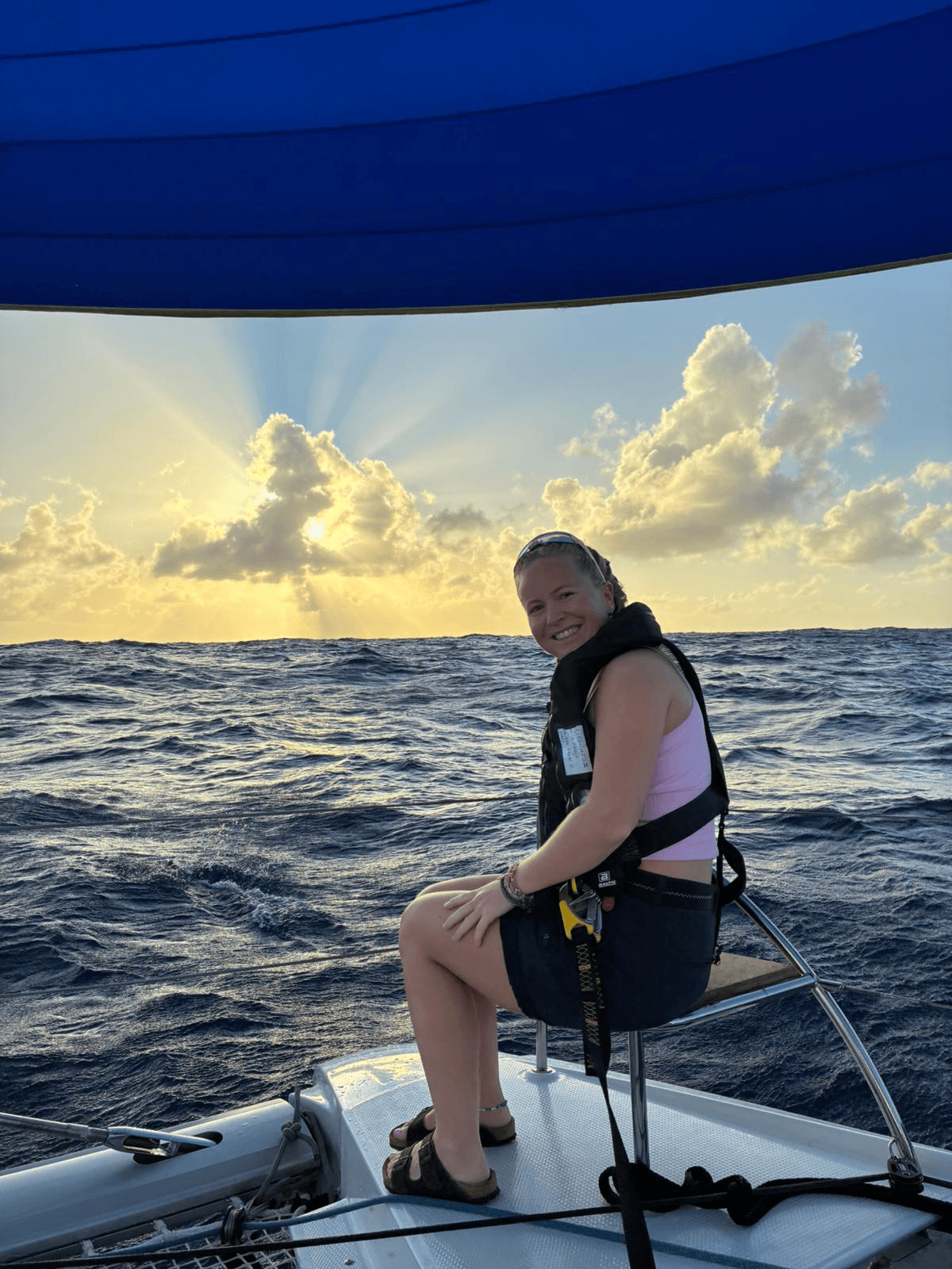 Man som står och tittar upp mot segeln med havet i bakgrunden