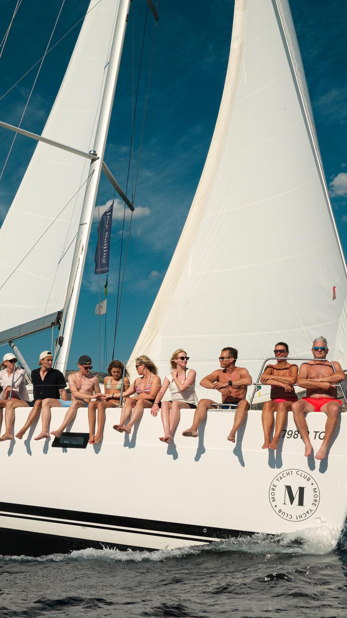 Åtta deltagare sitter på kanten av segelbåten och dinglar med benen