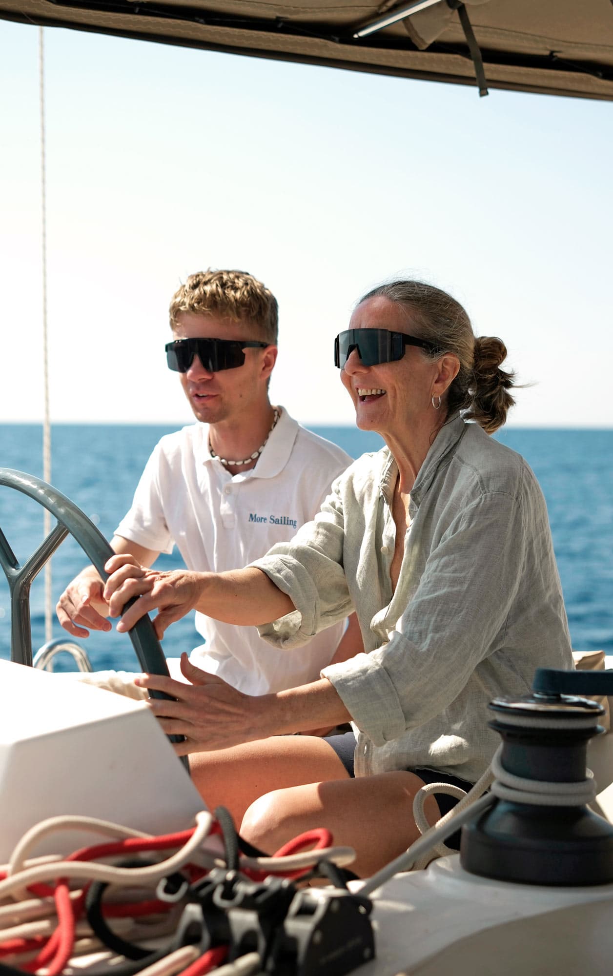 A skipper shows a female guest how to steer the boat