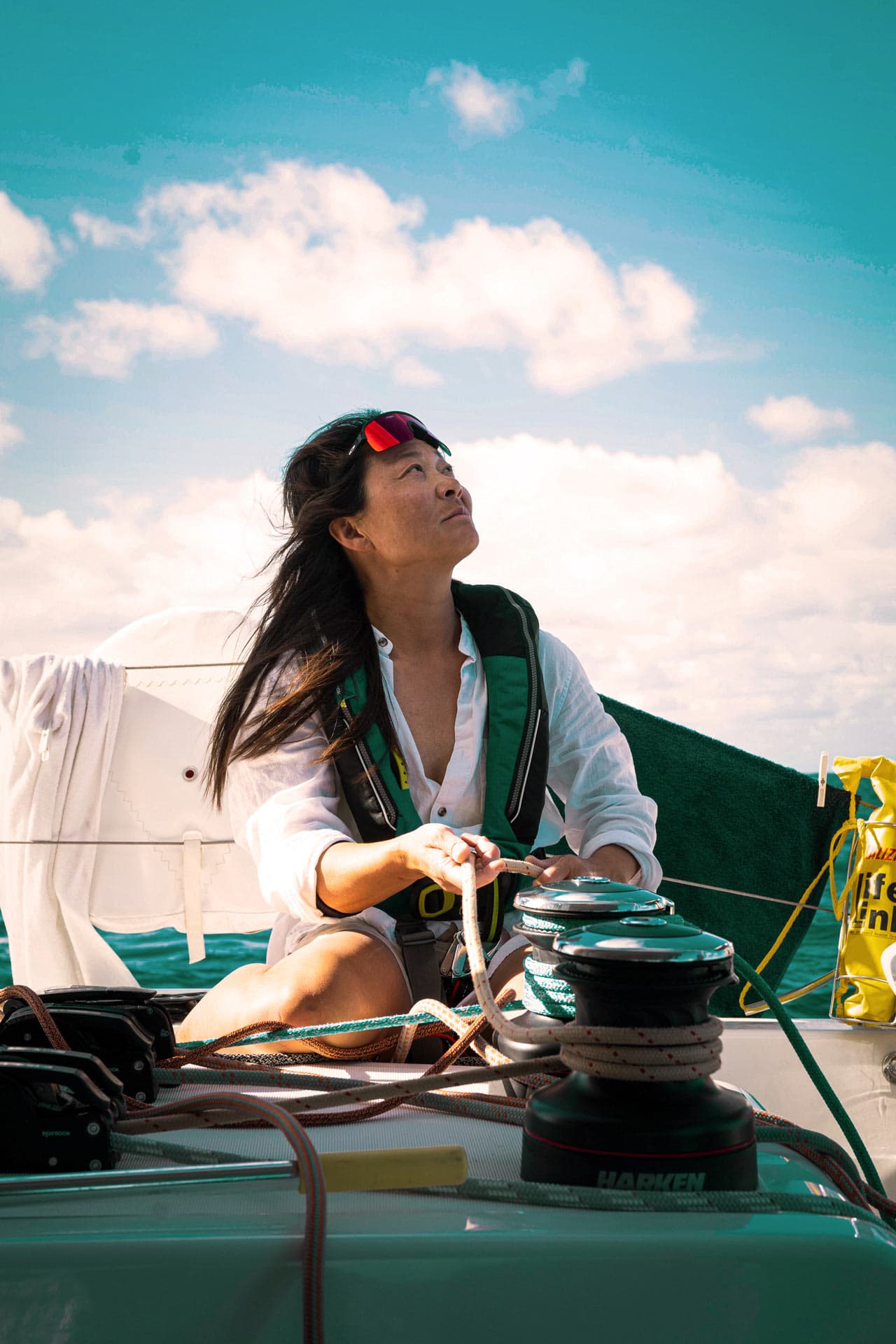 Eine gut ausgerüstete Frau bedient die Winschen, während sie auf das Großsegel schaut