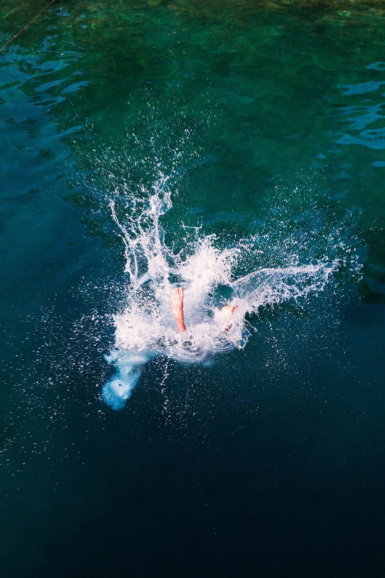 Morning dip in the sun. Two feet sticking out of the water in a splash