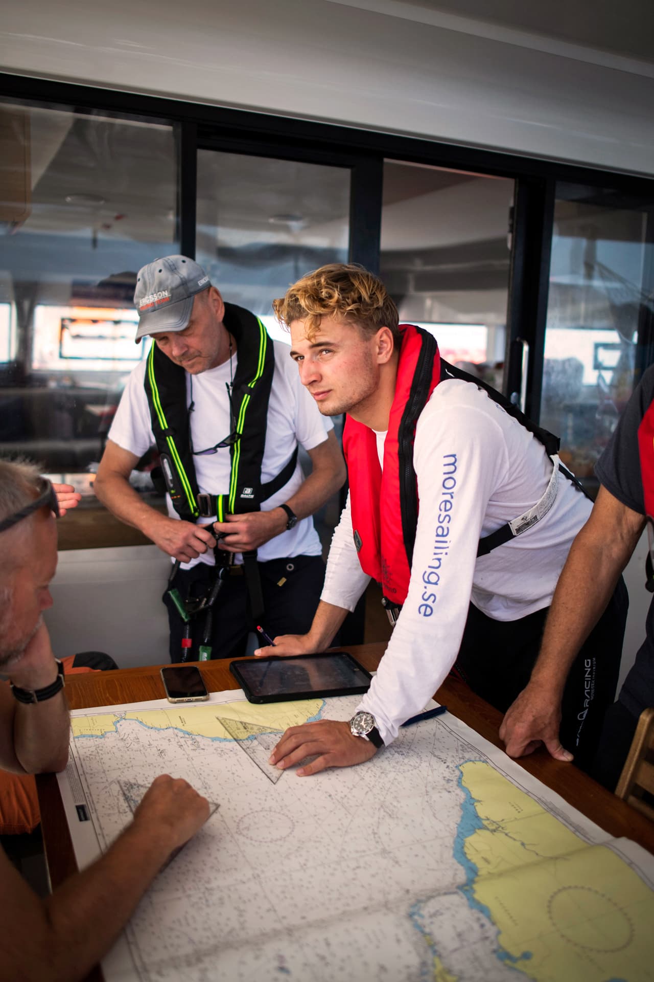 En grupp män med flytvästar betraktar ett sjökort.