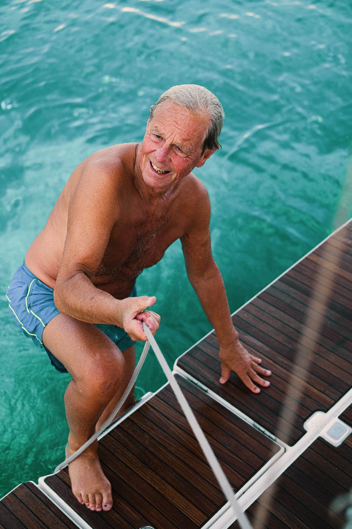 A man uses a rope to climb out of the sea after bathing