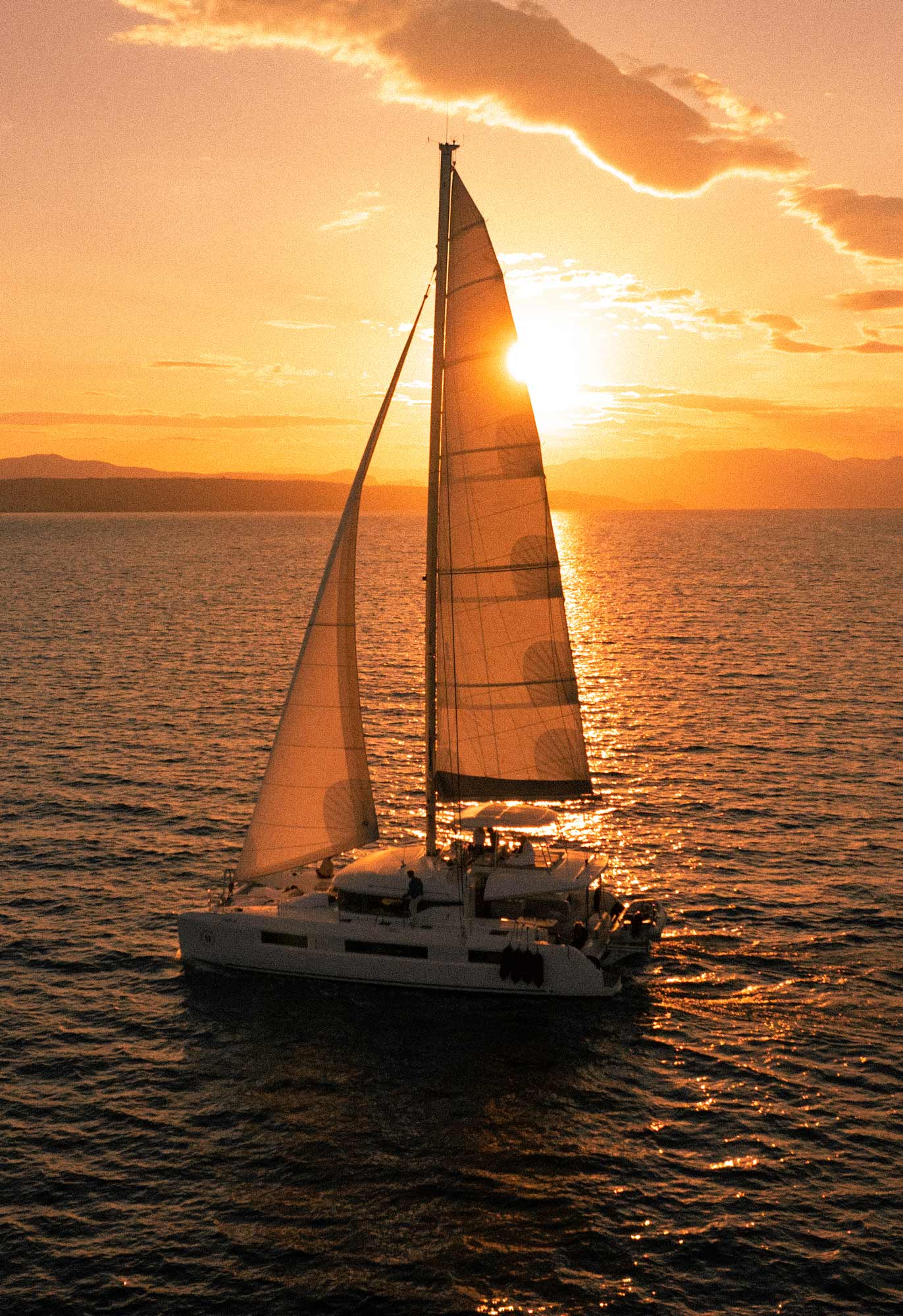 Catamaran sailing at sunrise