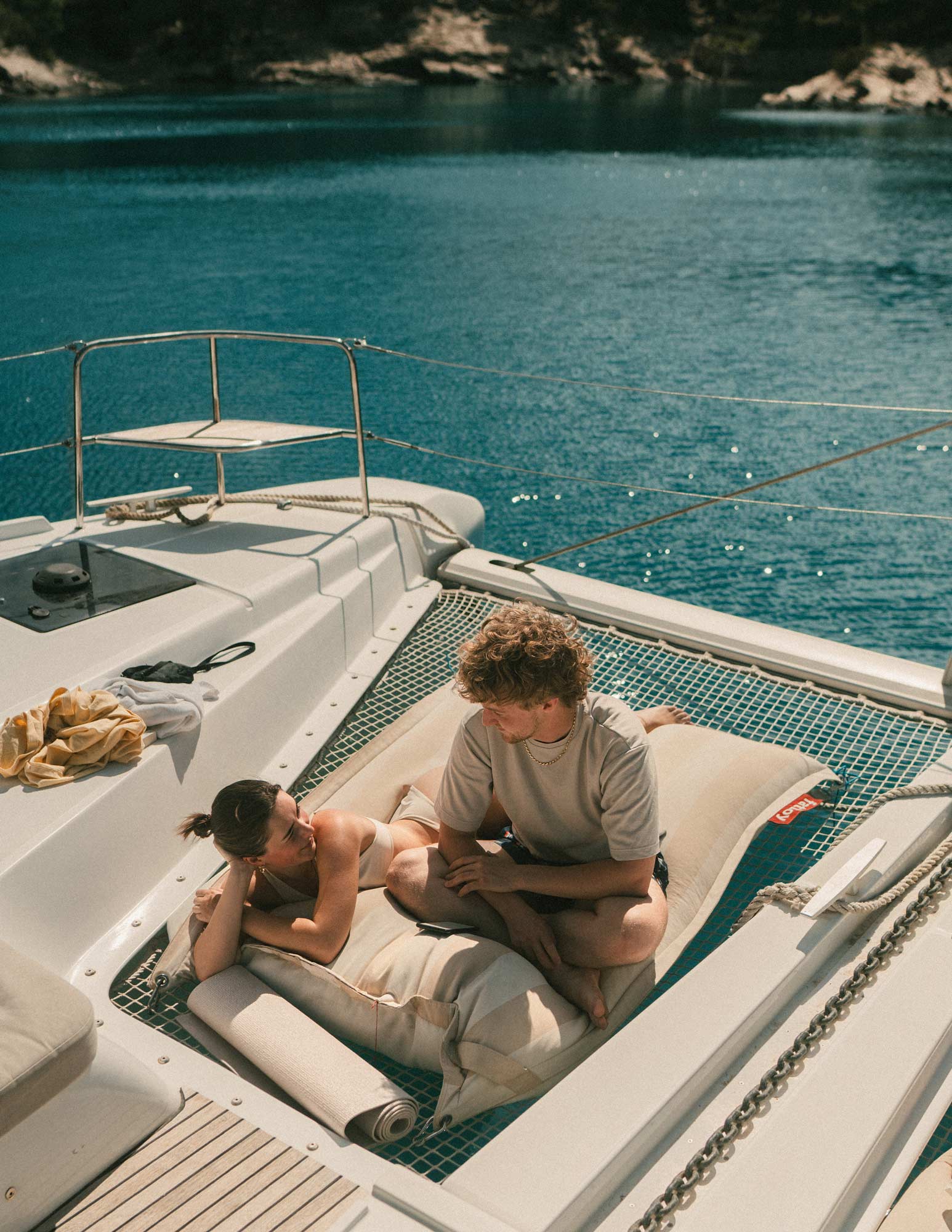 Two guests sunbathe in the catamaran’s net