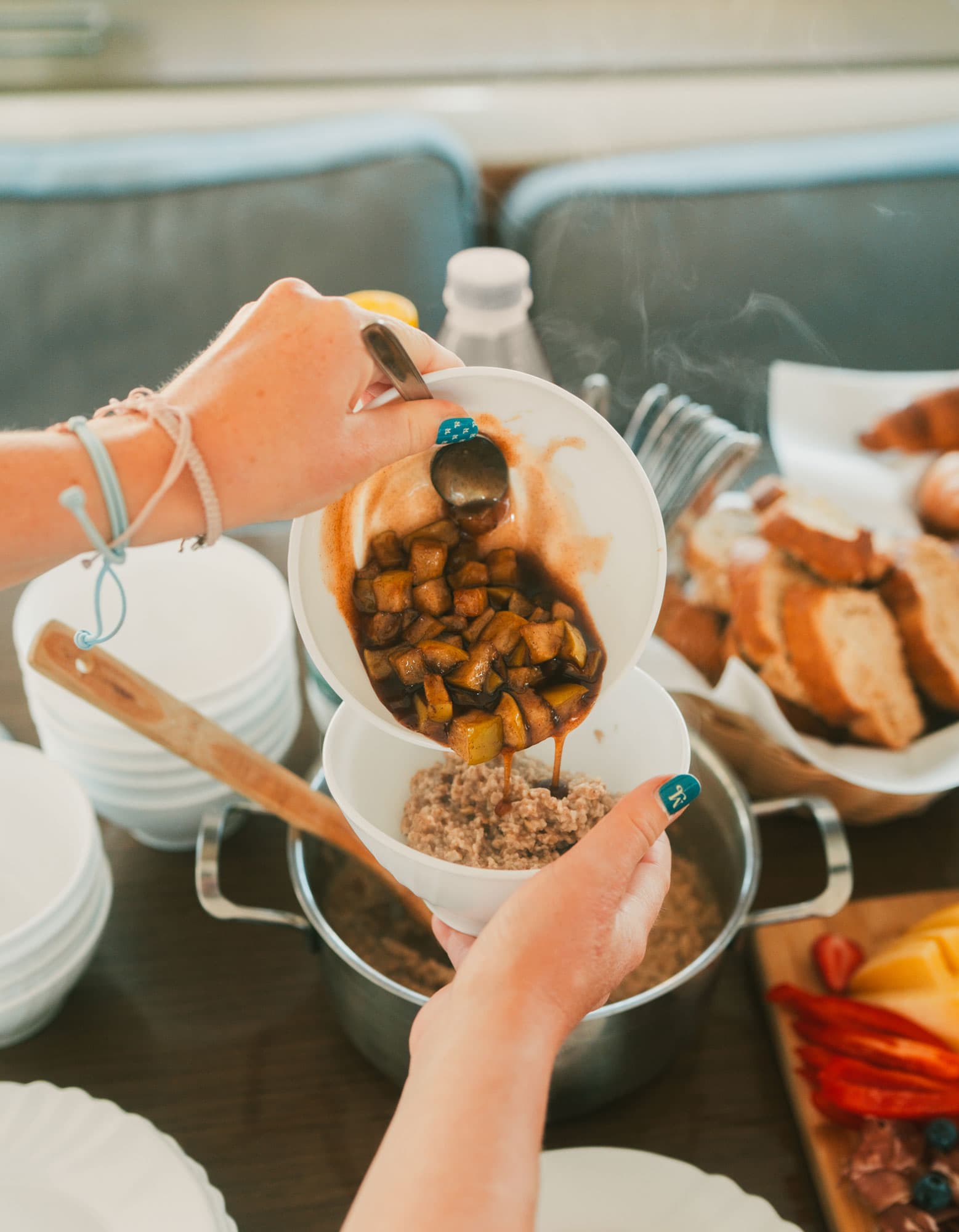 For breakfast, someone pours a mixture of apple and cinnamon over a bowl of porridge. 