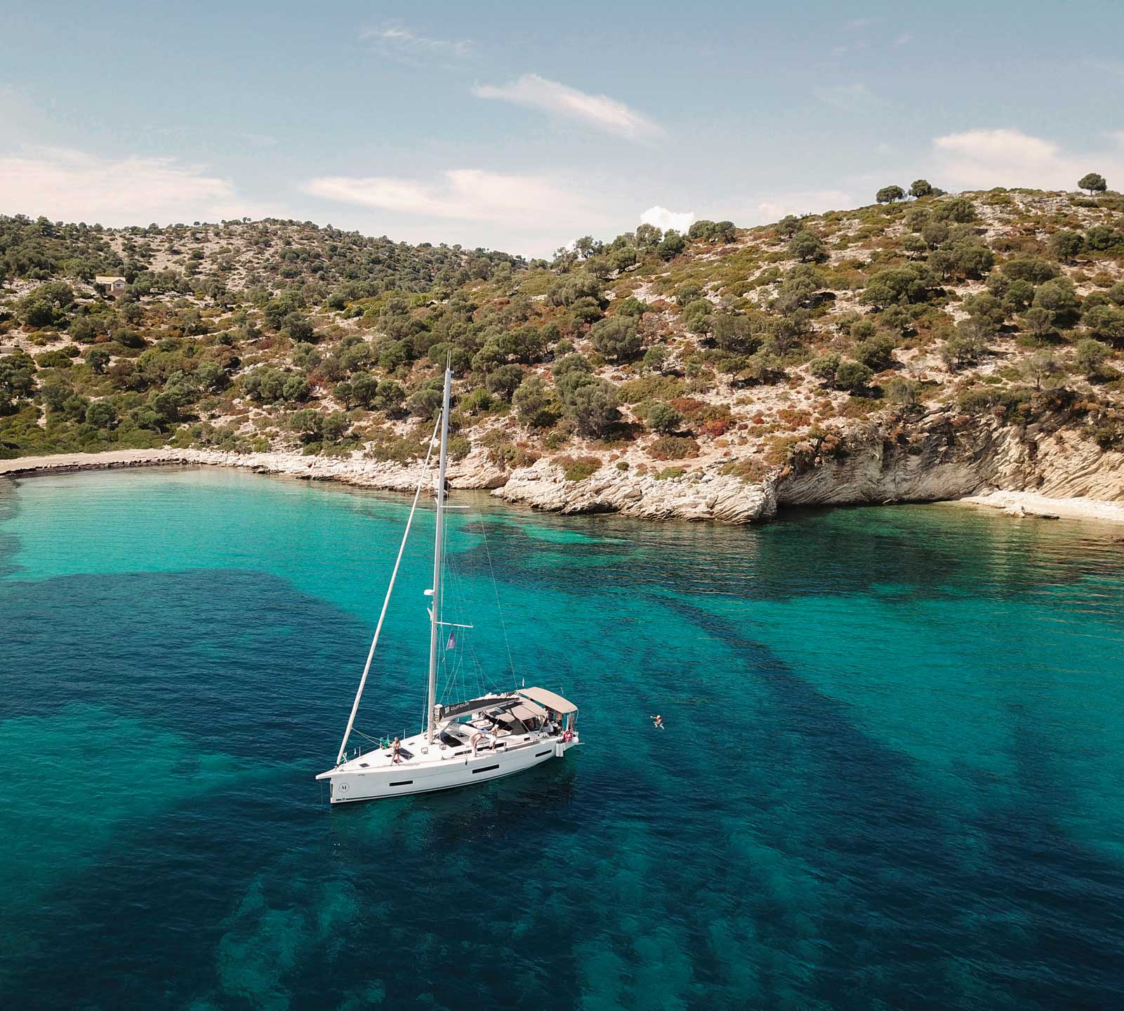 Enskrovs segelbåt ankrad vid badvik