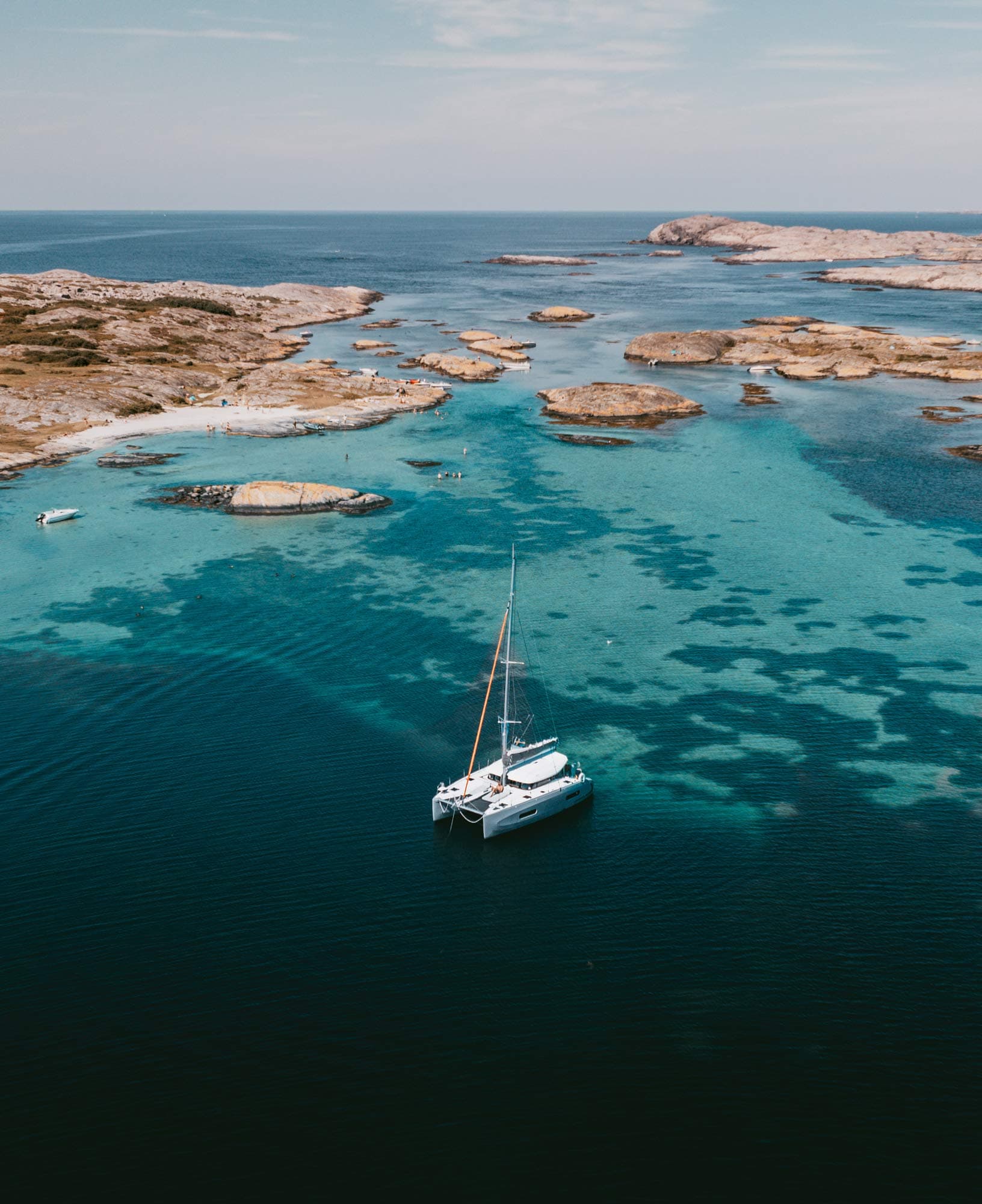 A catamaran floats, surrounded by small islands in the Swedish archipelago