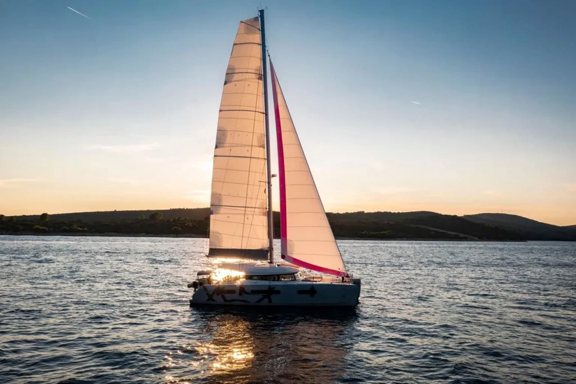 The Excess 15 catamaran sailing at sunset.