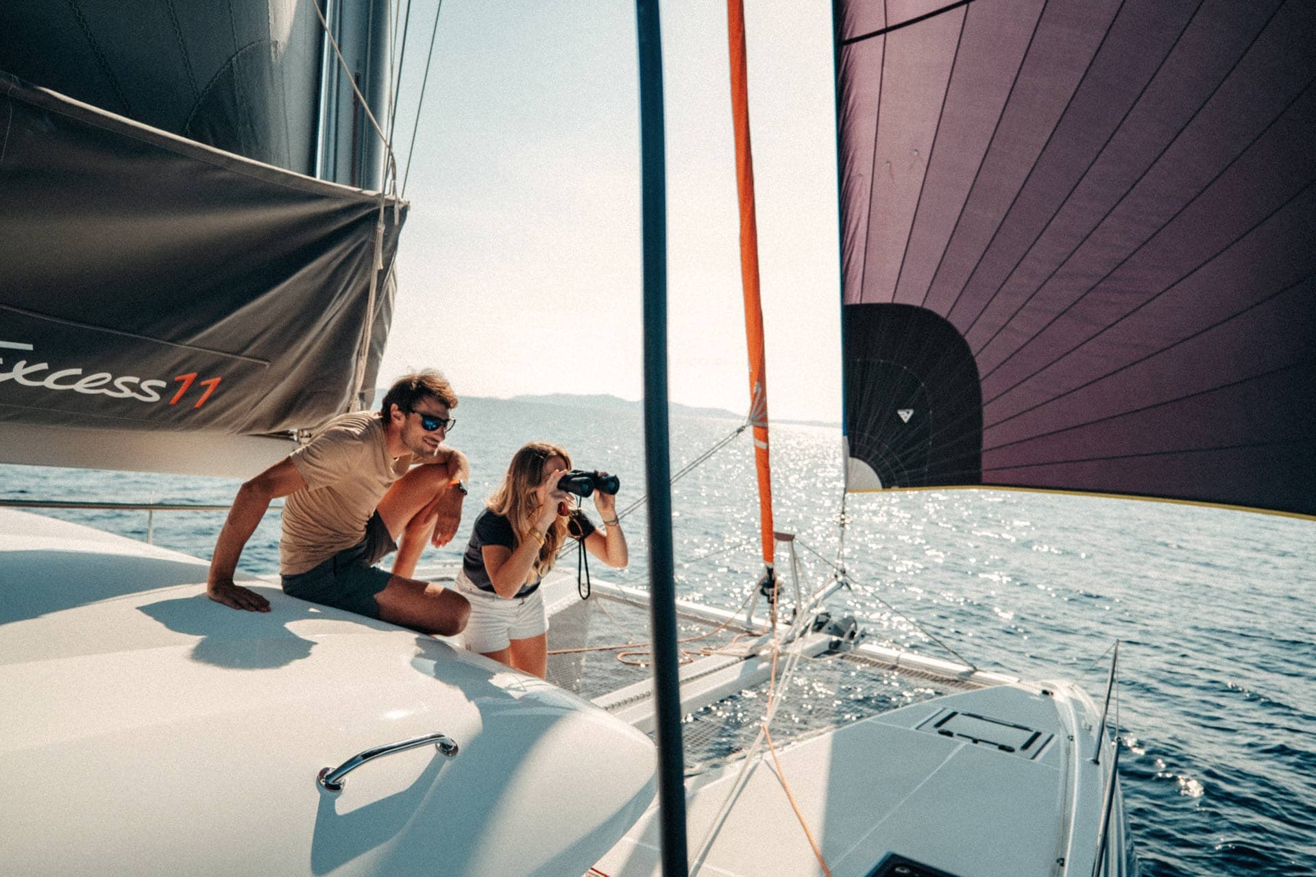 En kvinna står med kikare och en man sitter bredvid och tittar ut