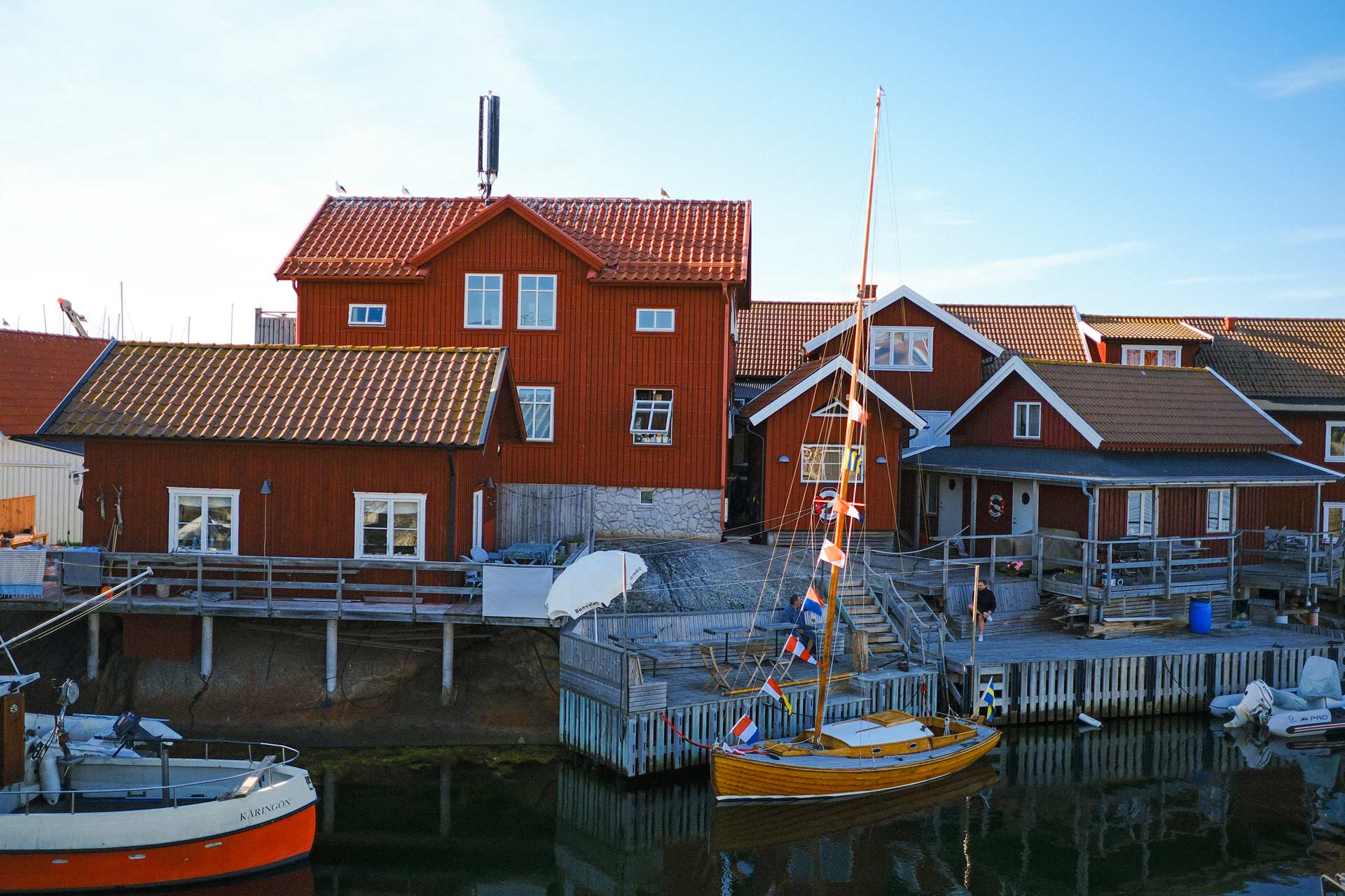A view of Käringön harbour, with a wooden sailboat with flags going up to the mast