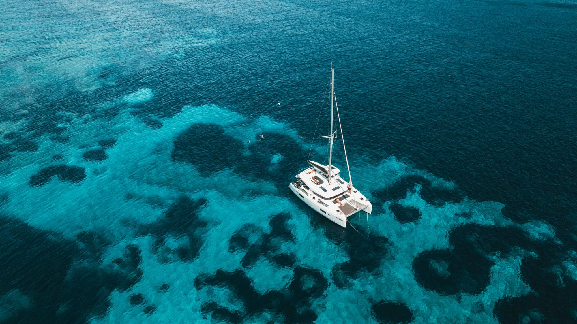 Ein Katamaran ankert im türkisfarbenen Wasser über einem schillernden Meeresgrund