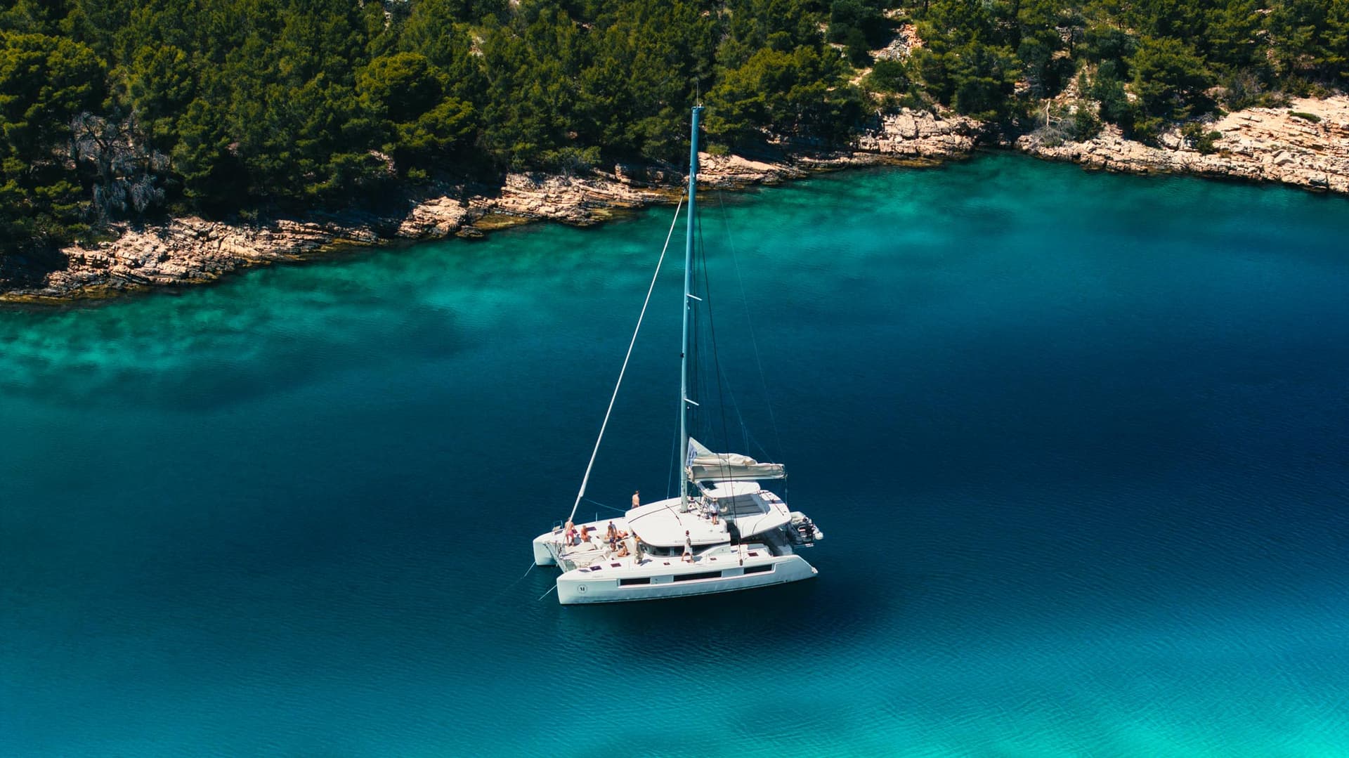 Ein Katamaran liegt in einer schönen Badebucht vor Anker