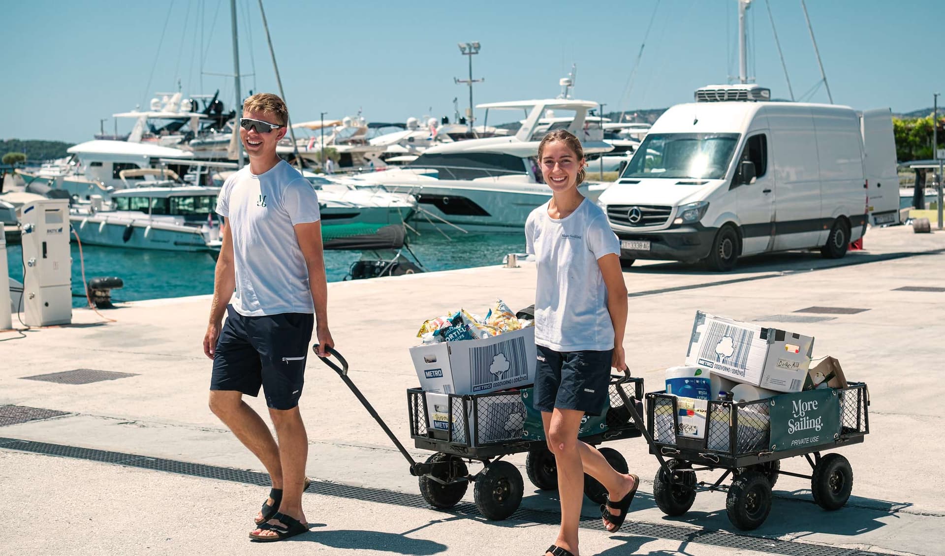 Zwei Mitarbeiter von More Sailing bringen Wagen voller Verpflegung an Bord