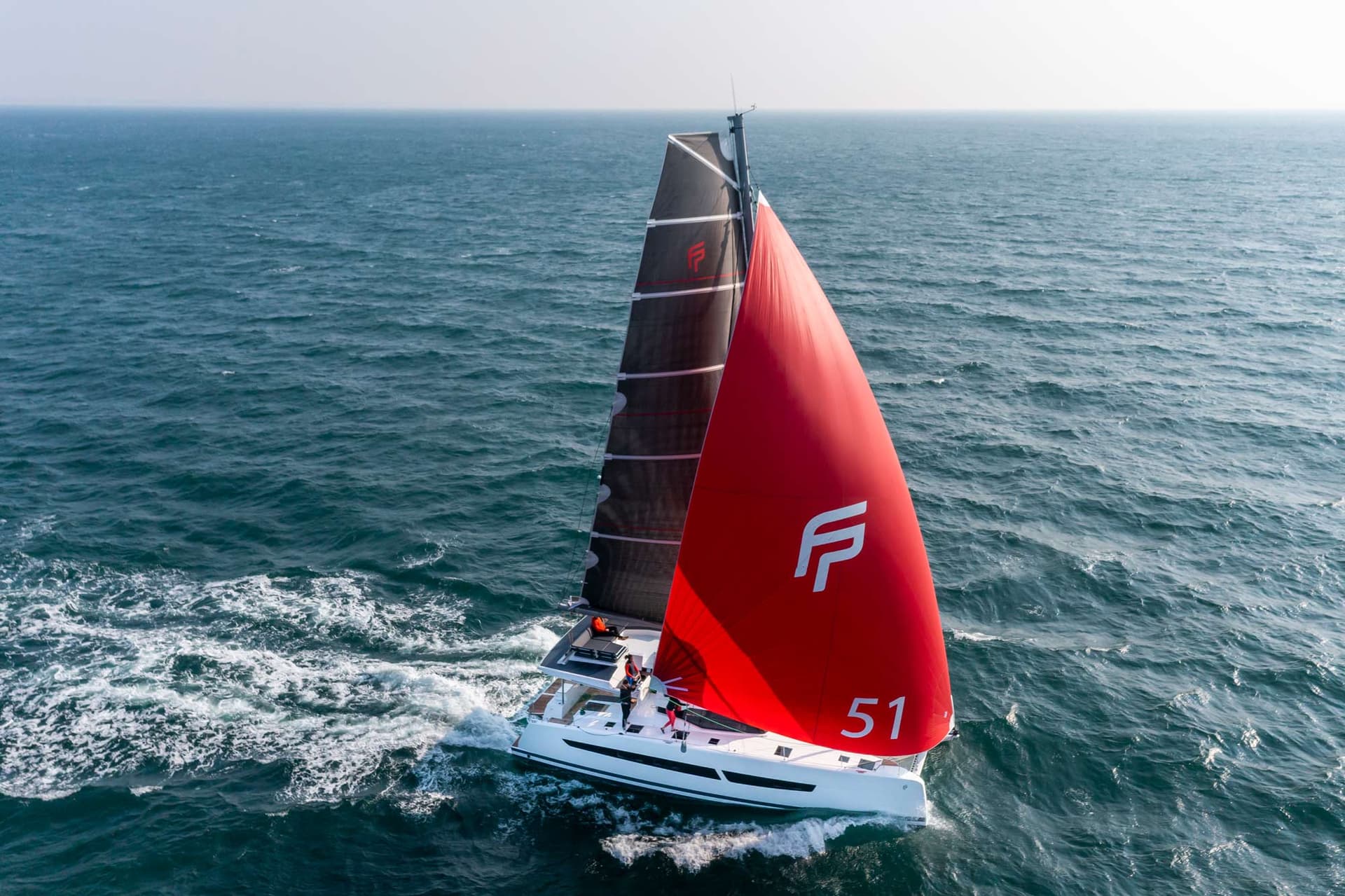 Einsegelnder Aura 51 auf See, ein Katamaran mit einem schwarzen und einem roten Segel