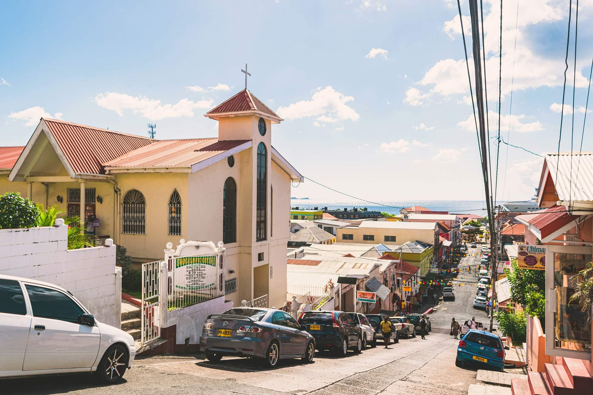 Town street in Grenada, cars parked outside a church.