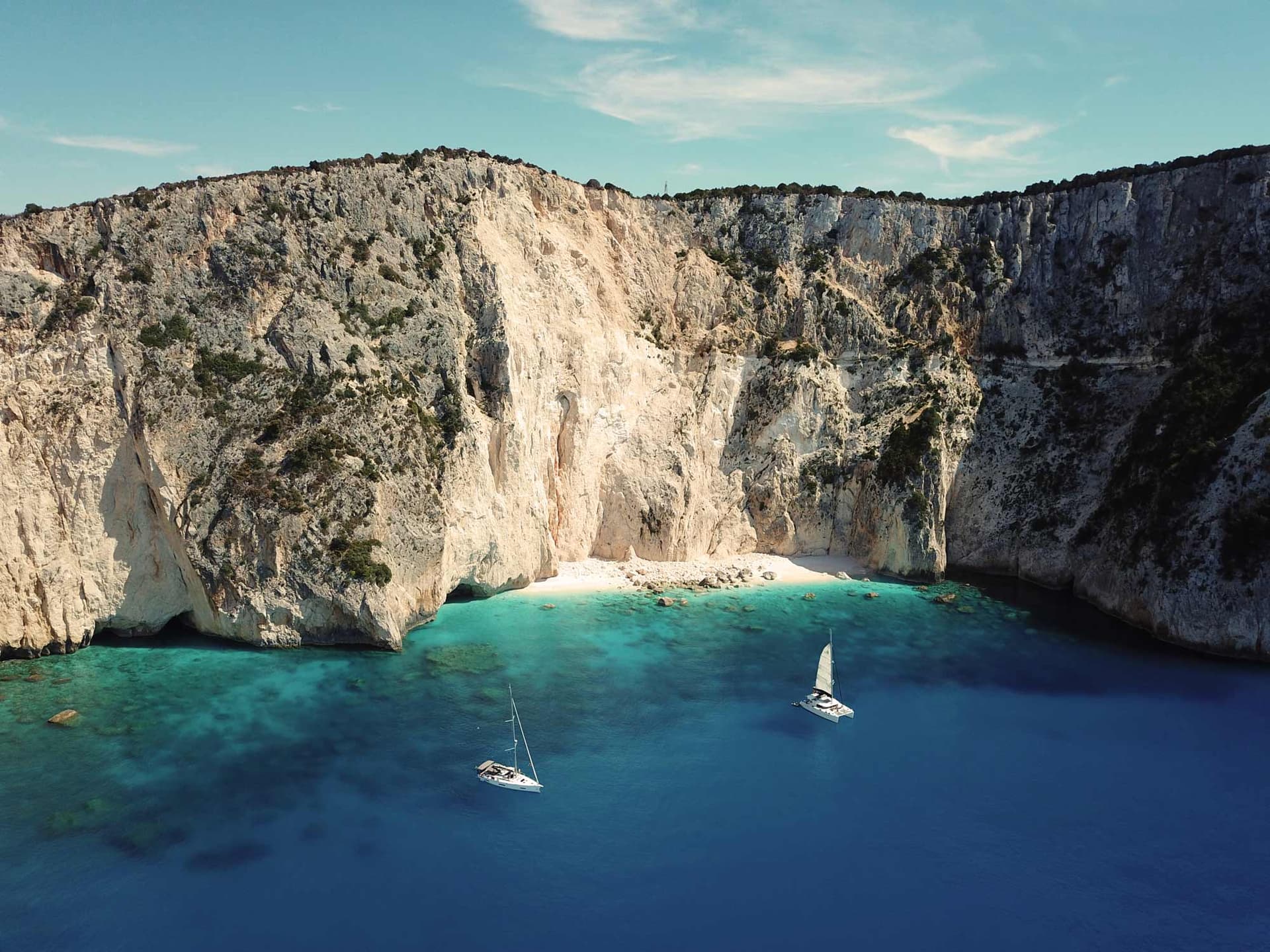 Im Mittelmeer vor einer hohen Klippe ankerndes Segelboot