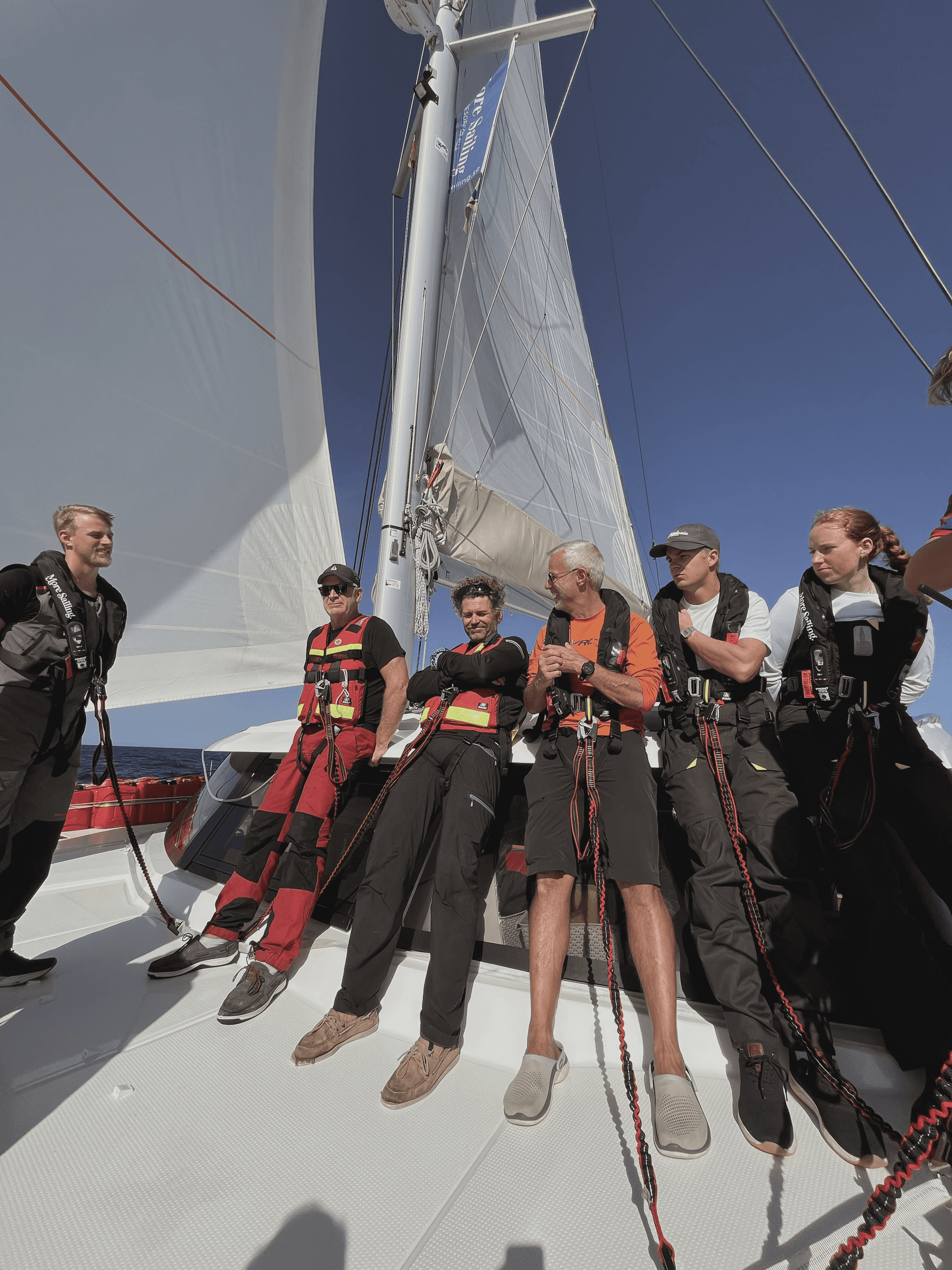 Kurseltagare står på däck i solen på en katamaran 