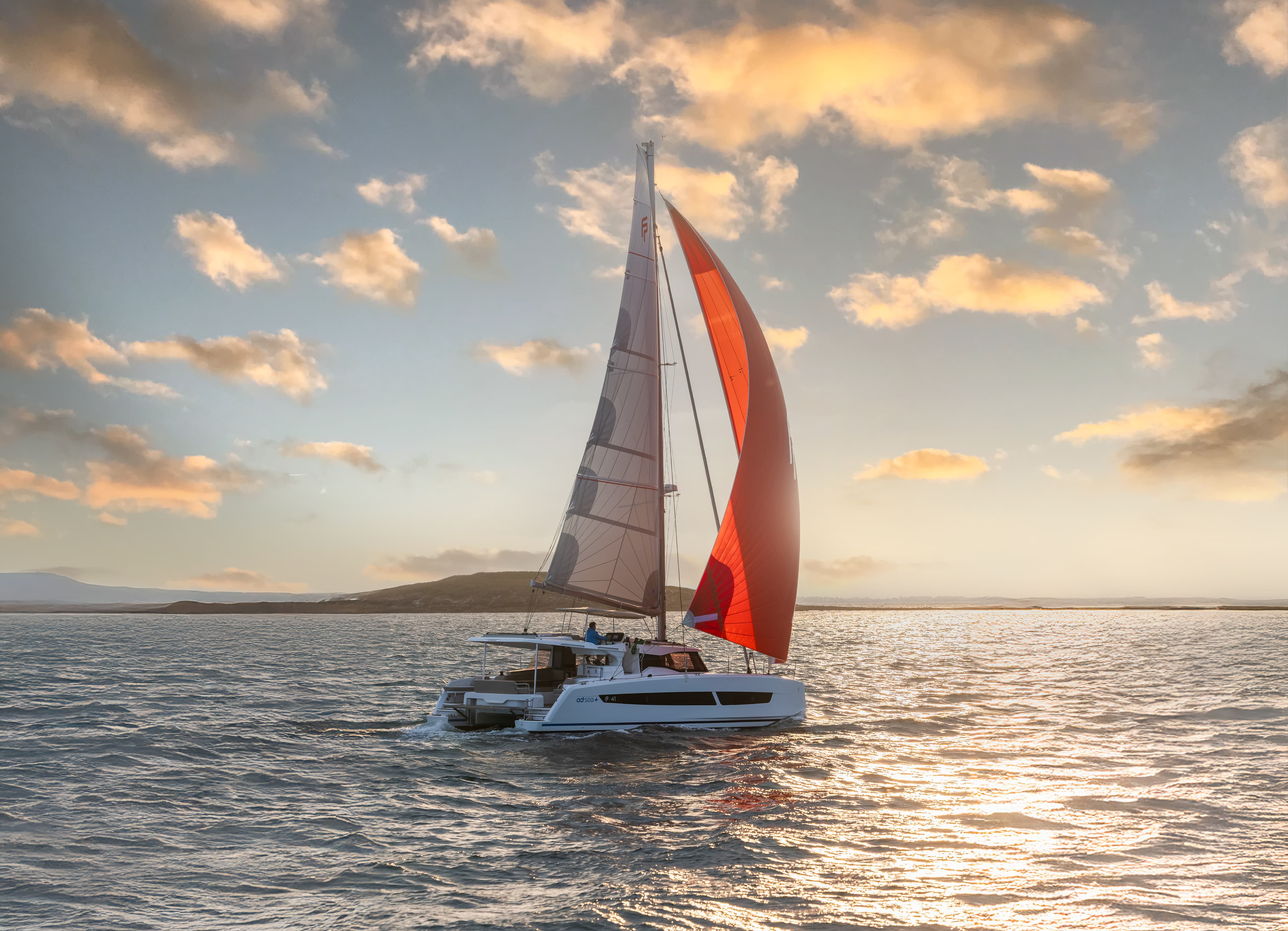 Katamaran ligger ankrad i vattnet vid solnedgång.