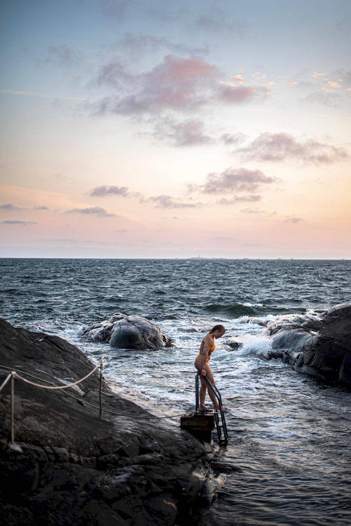 Reiseziel Åstol, eine Frau steigt eine Badeleiter am Meer hinunter.