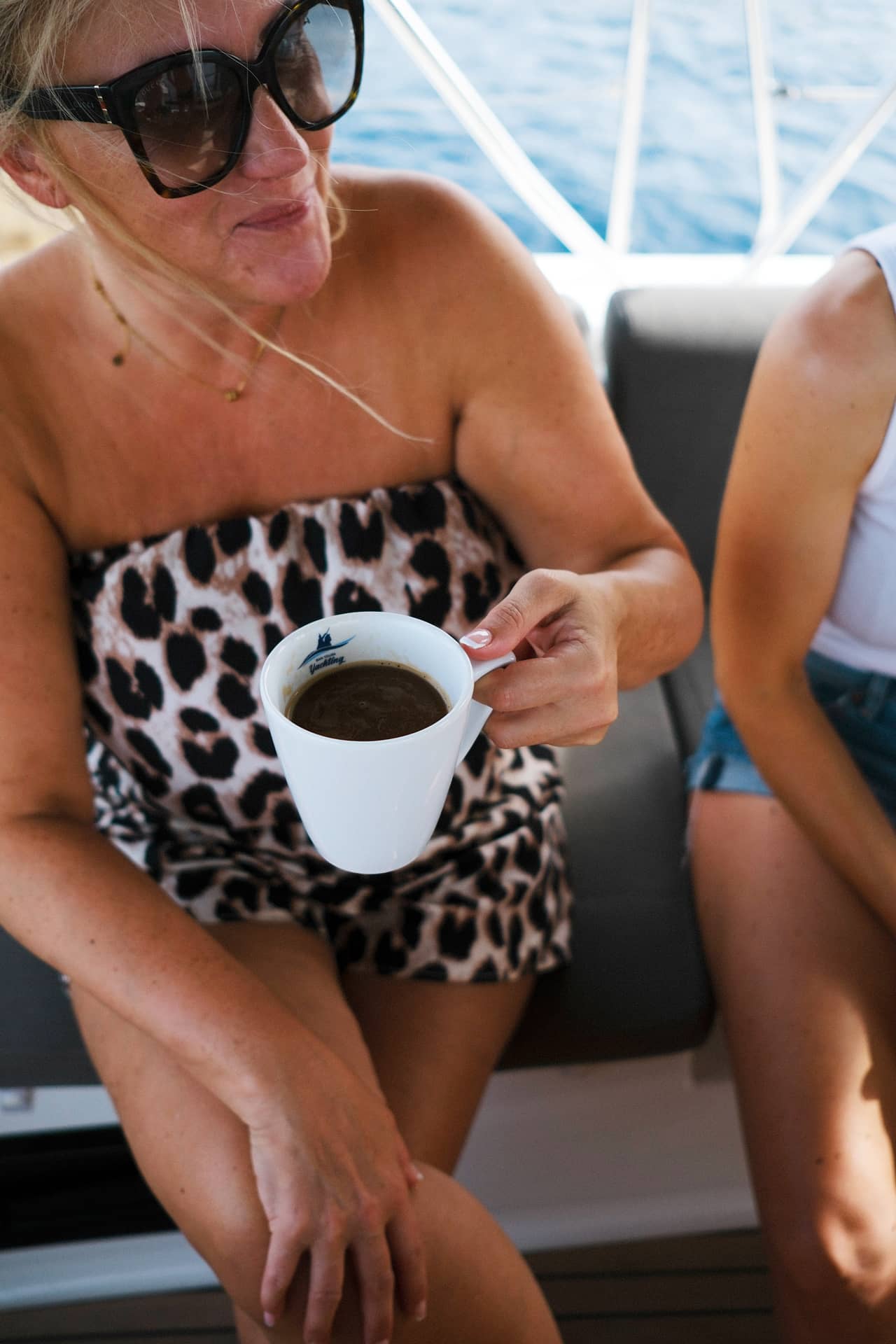 Eine Frau im Leopardenkleid, die eine Tasse schwarzen Kaffee hält