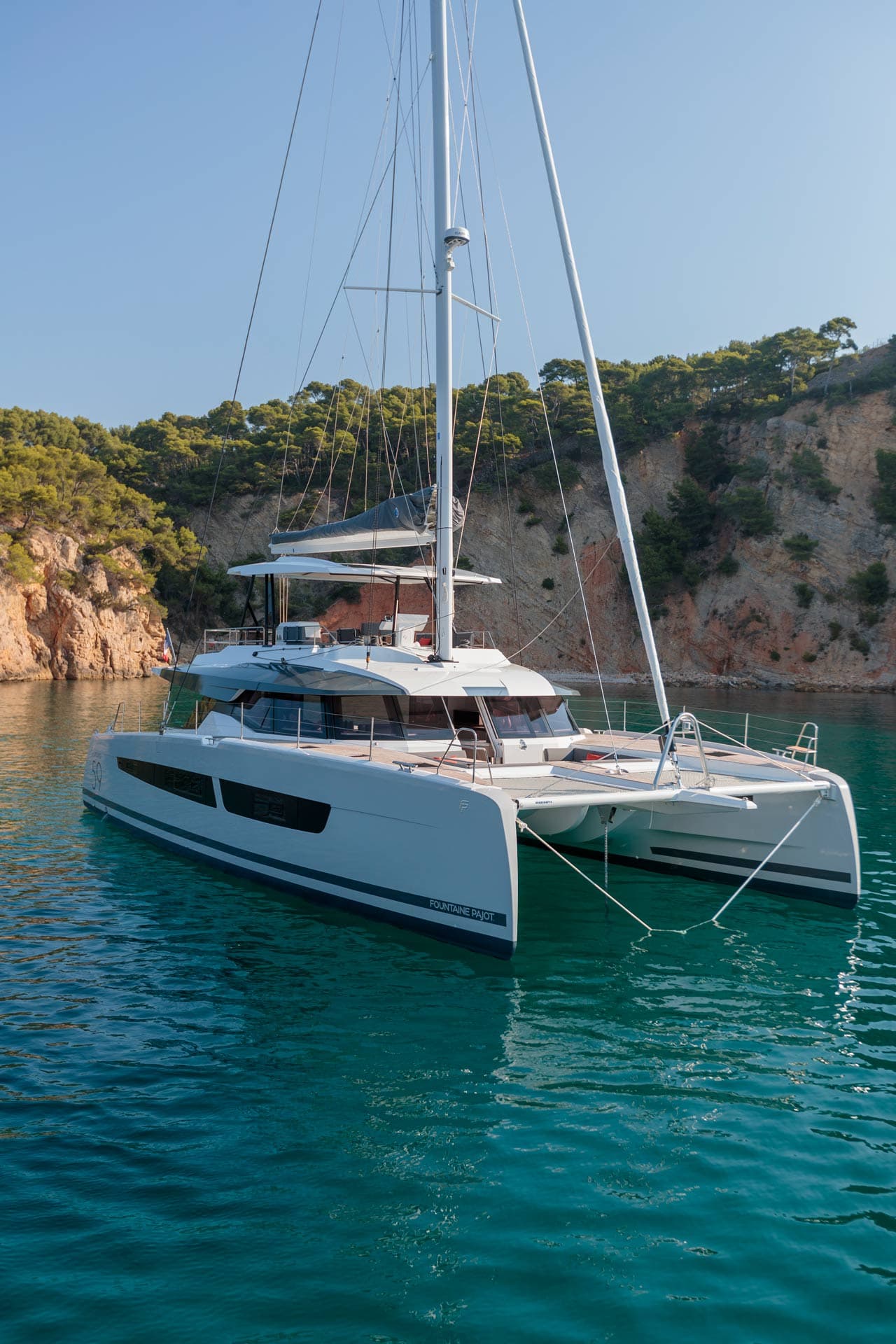 Katamaran ligger ankrad i en vik med turkost vatten.