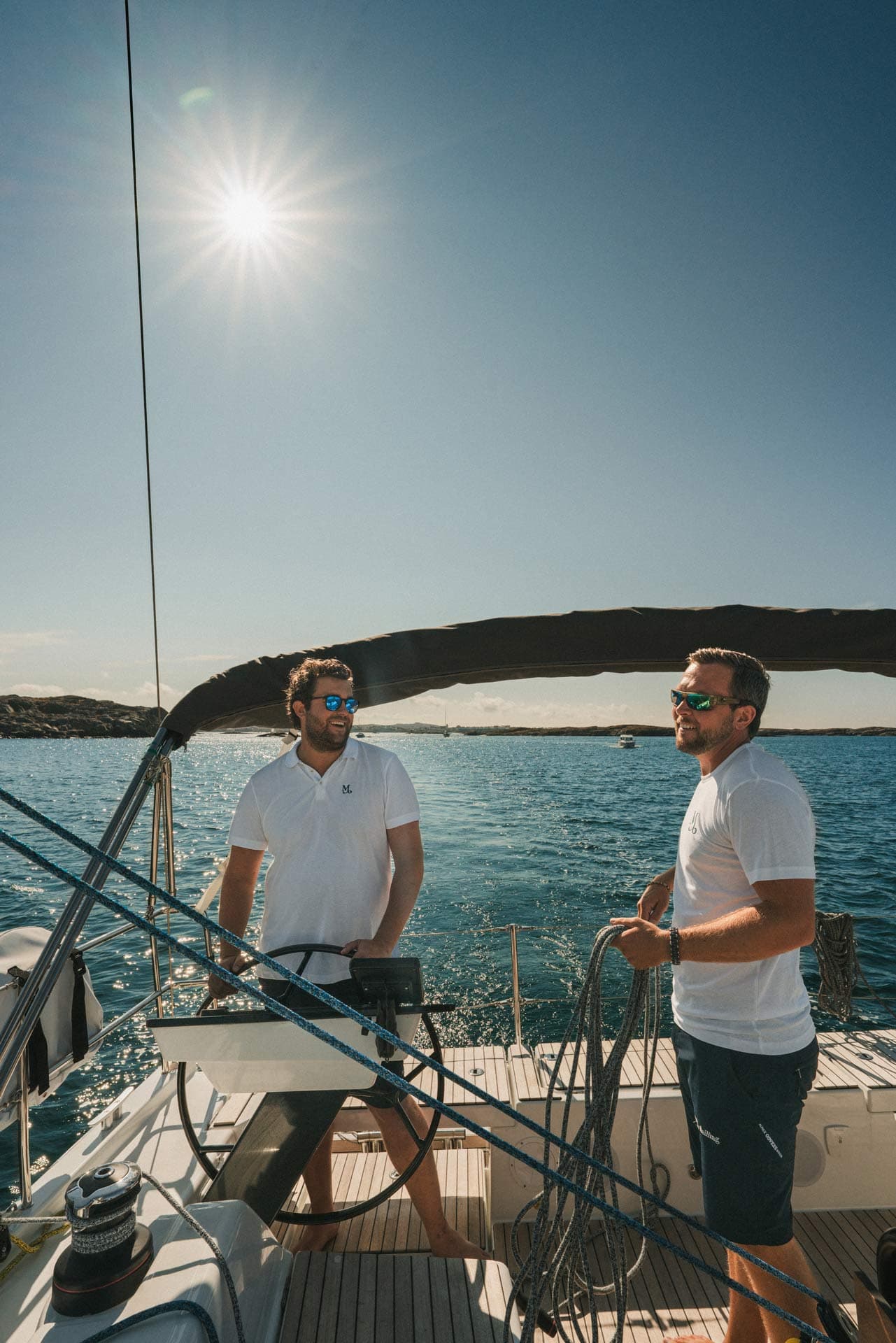 Zwei Skipper haben Spaß an Bord, einer steuert, der andere hält eine Leine
