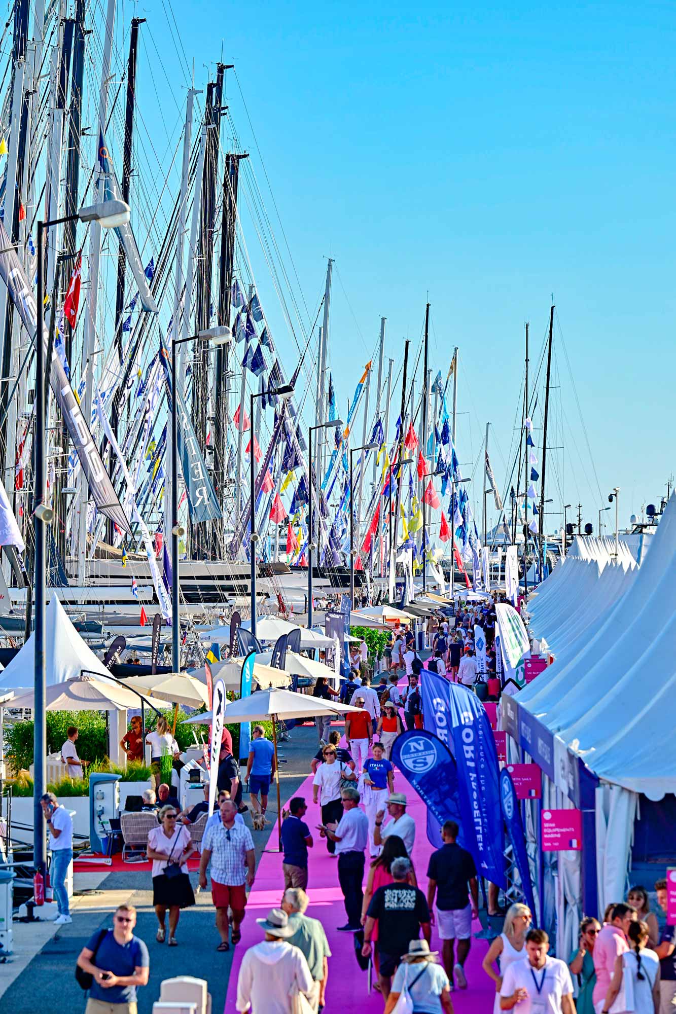 Festivalstråk, rosa matta där många människor går. Fullt med färgstarka flaggor