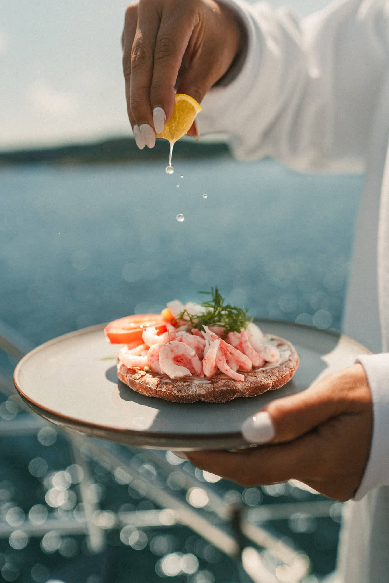Krabbensandwich mit Tomate und Dill. Darüber wird eine Zitrone ausgepresst