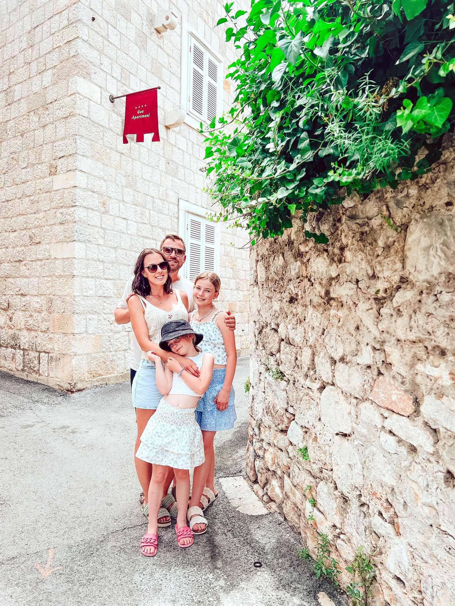 Sommerlich gekleidete Familie posiert an einer Mauer
