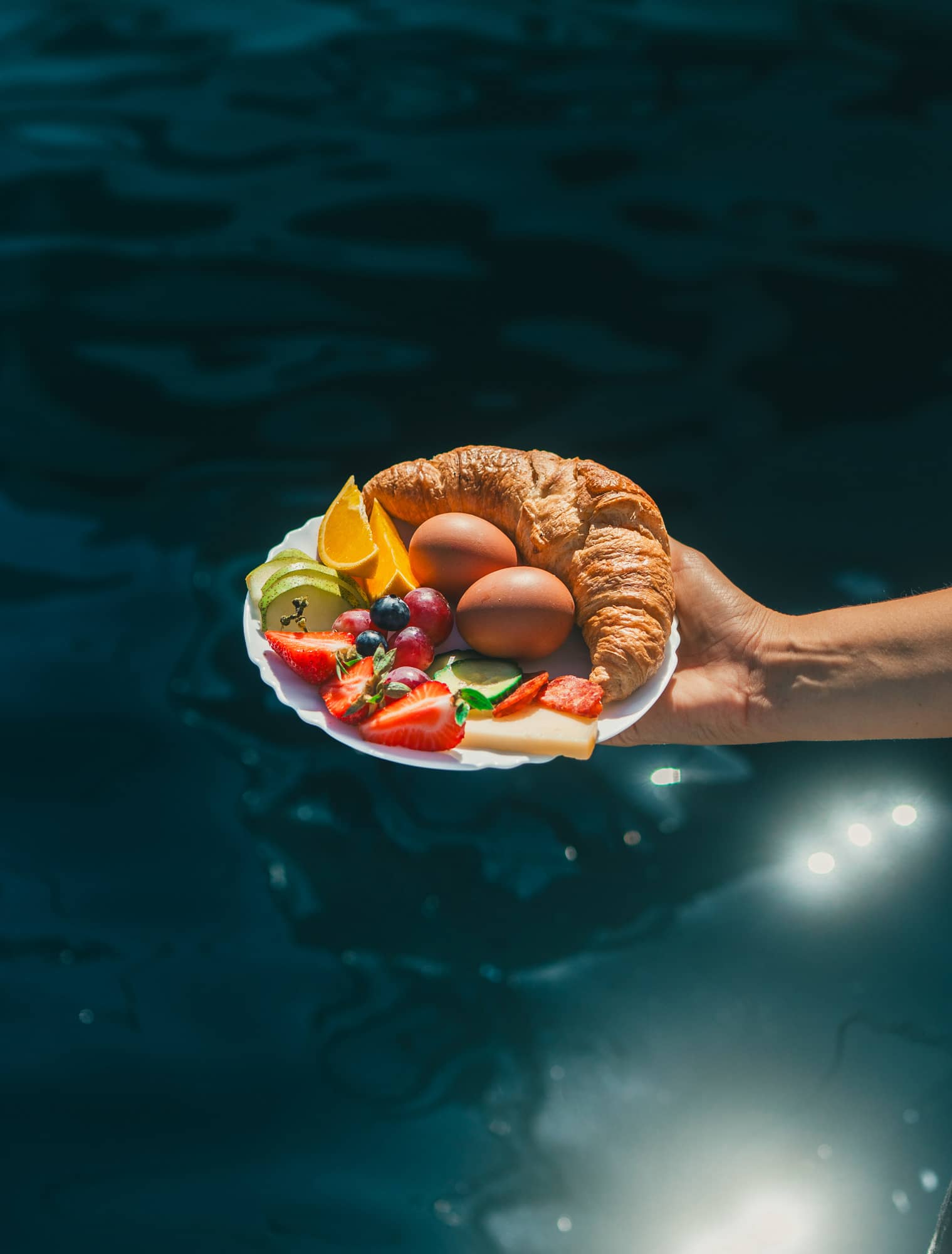 Ein Frühstücksteller mit Croissant, Eiern, Käse und Obst