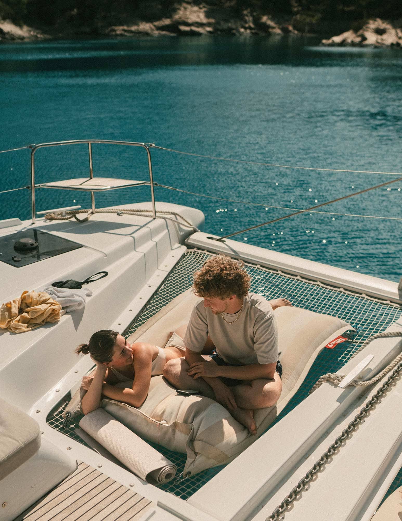 Två gäster solar i katamaranens nät