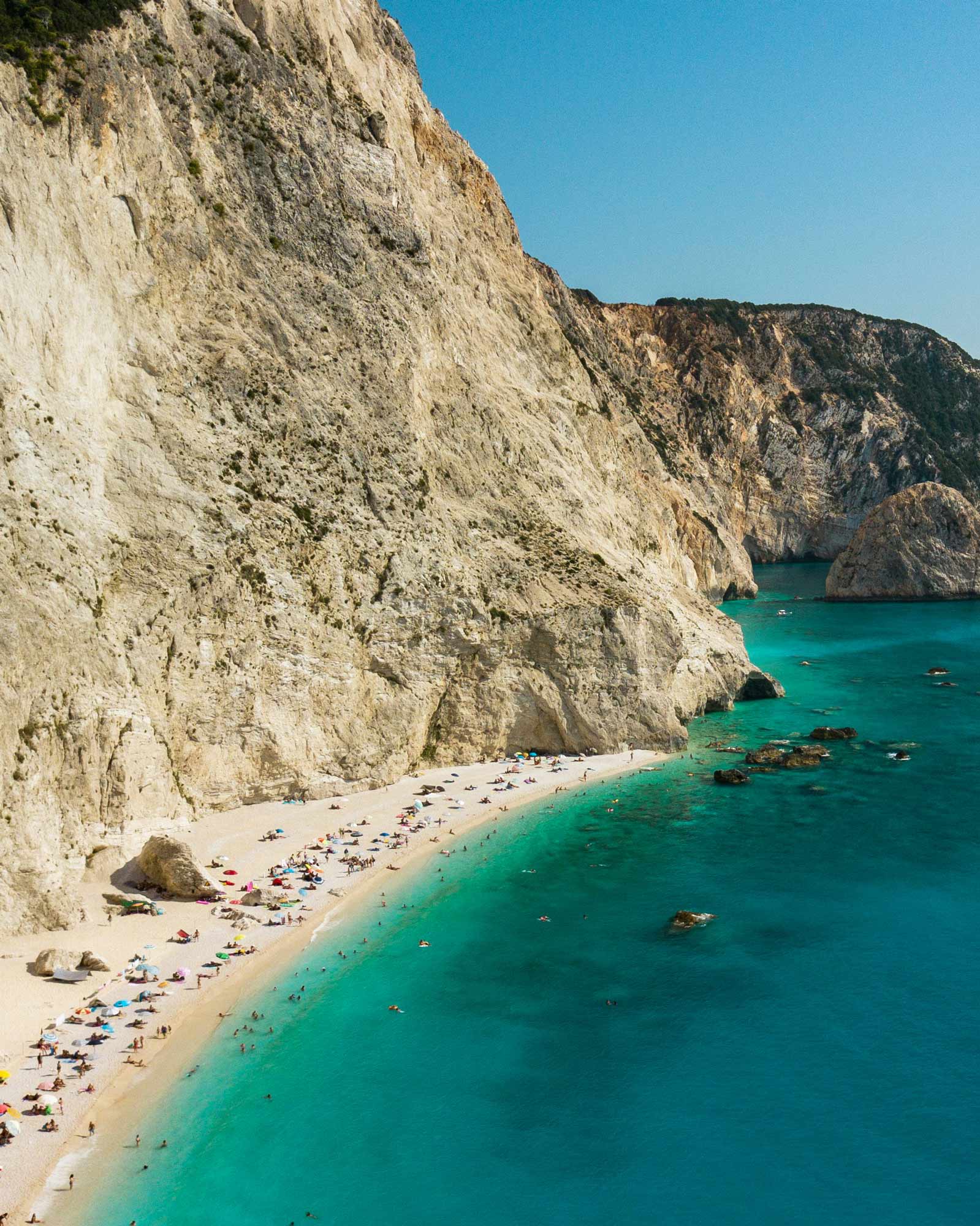 Ein Strand mit farbenfrohen Handtüchern und Sonnenschirm auf Lefkas