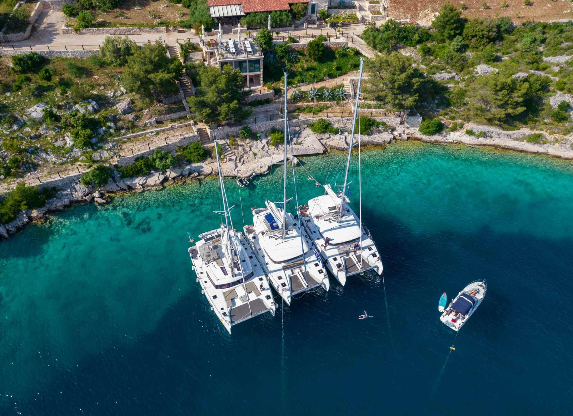 Three catamarans alongside each other while conference delegates swim