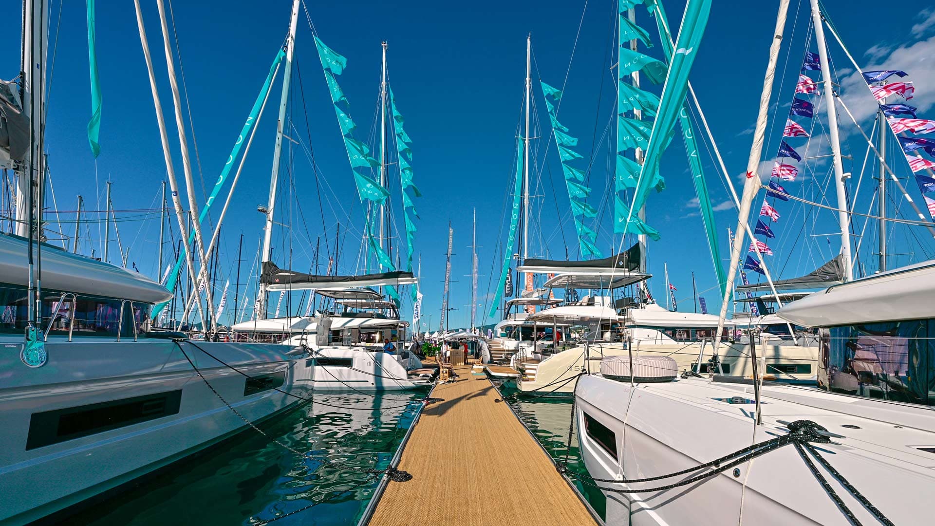 Segelbåtar liggandes med flaggor på båda sidor om en brygga