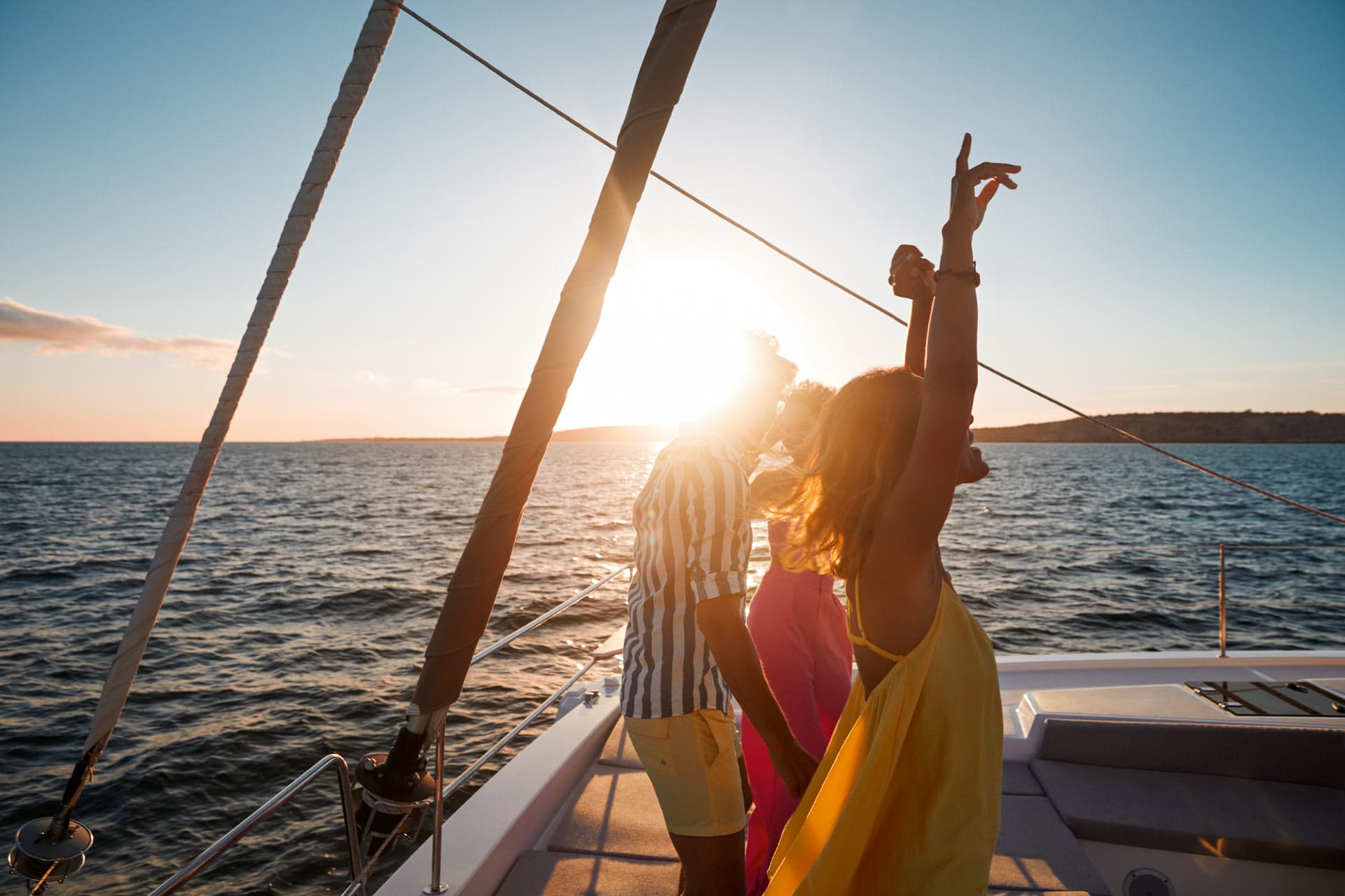 Kvinna i gul klänning dansar med sällskap på en segelbåt.