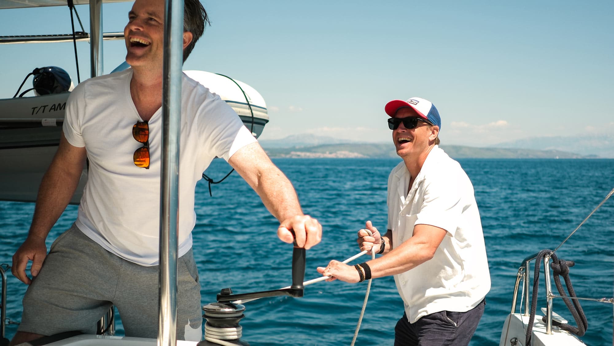 Två glada män som hjälps åt att vinscha under seglarkurs