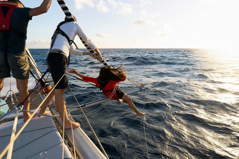 Tre i besättningen utför en procedur för seglet